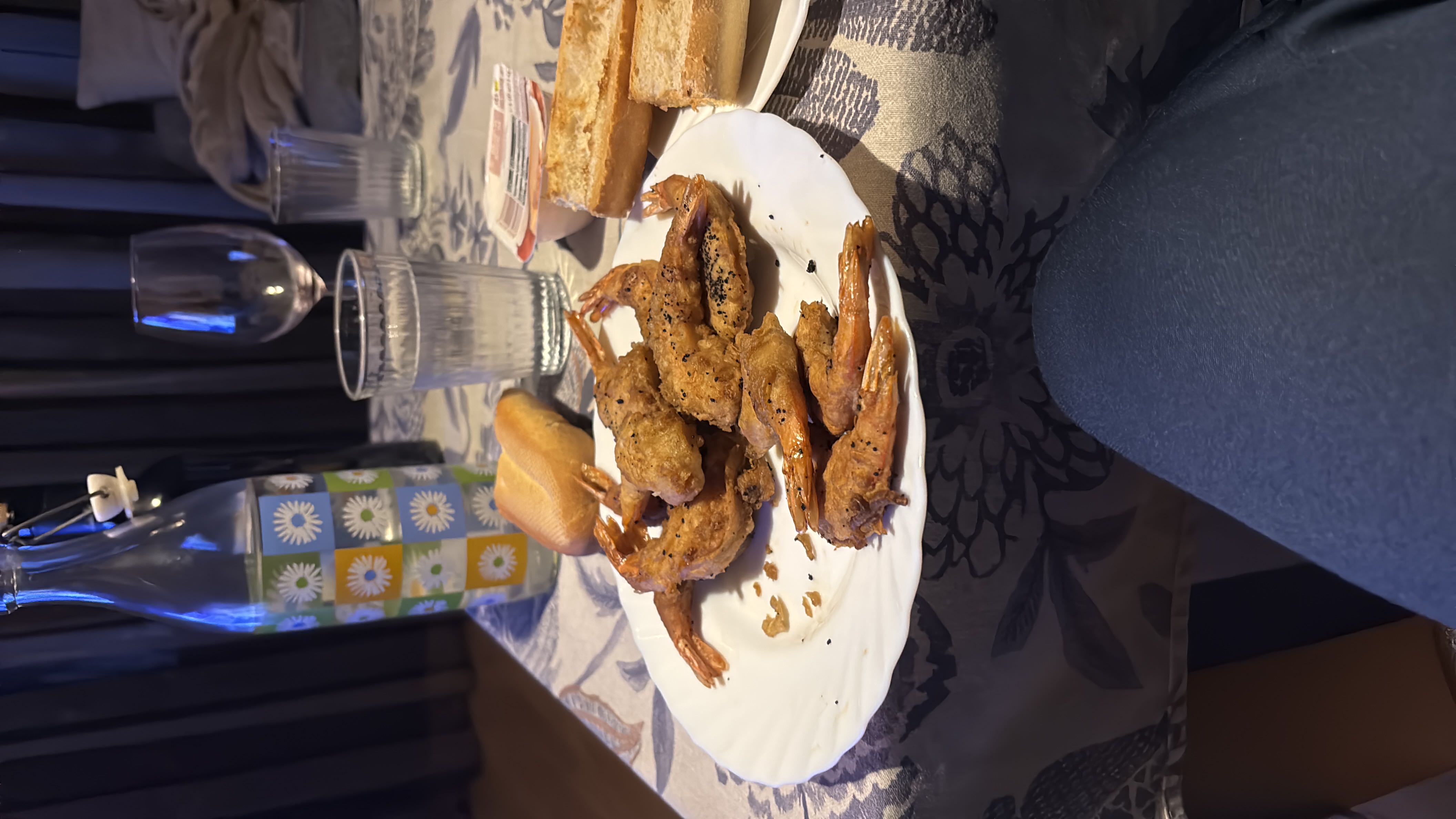 A meal consisting of fried shrimp, bread, and butter, served with water and wine.