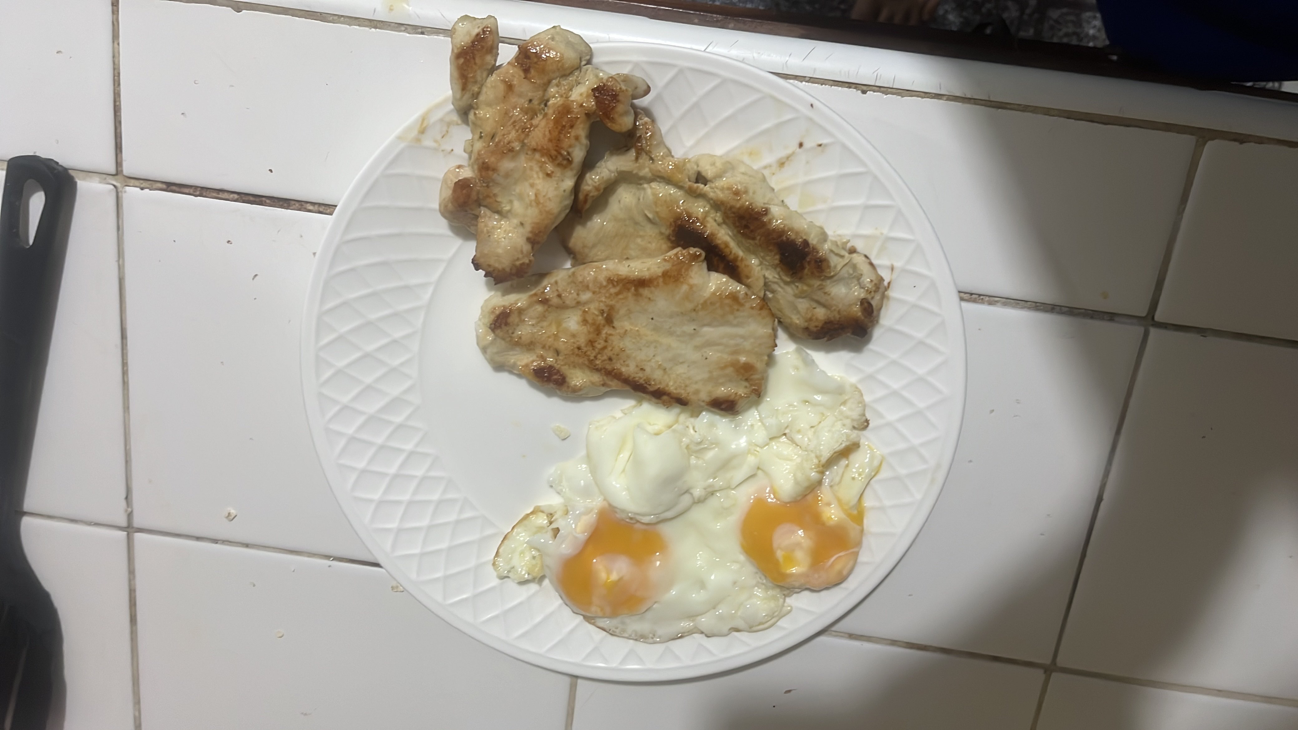 A high-protein meal consisting of fried eggs and grilled chicken breast, low in carbohydrates and moderate in fats.