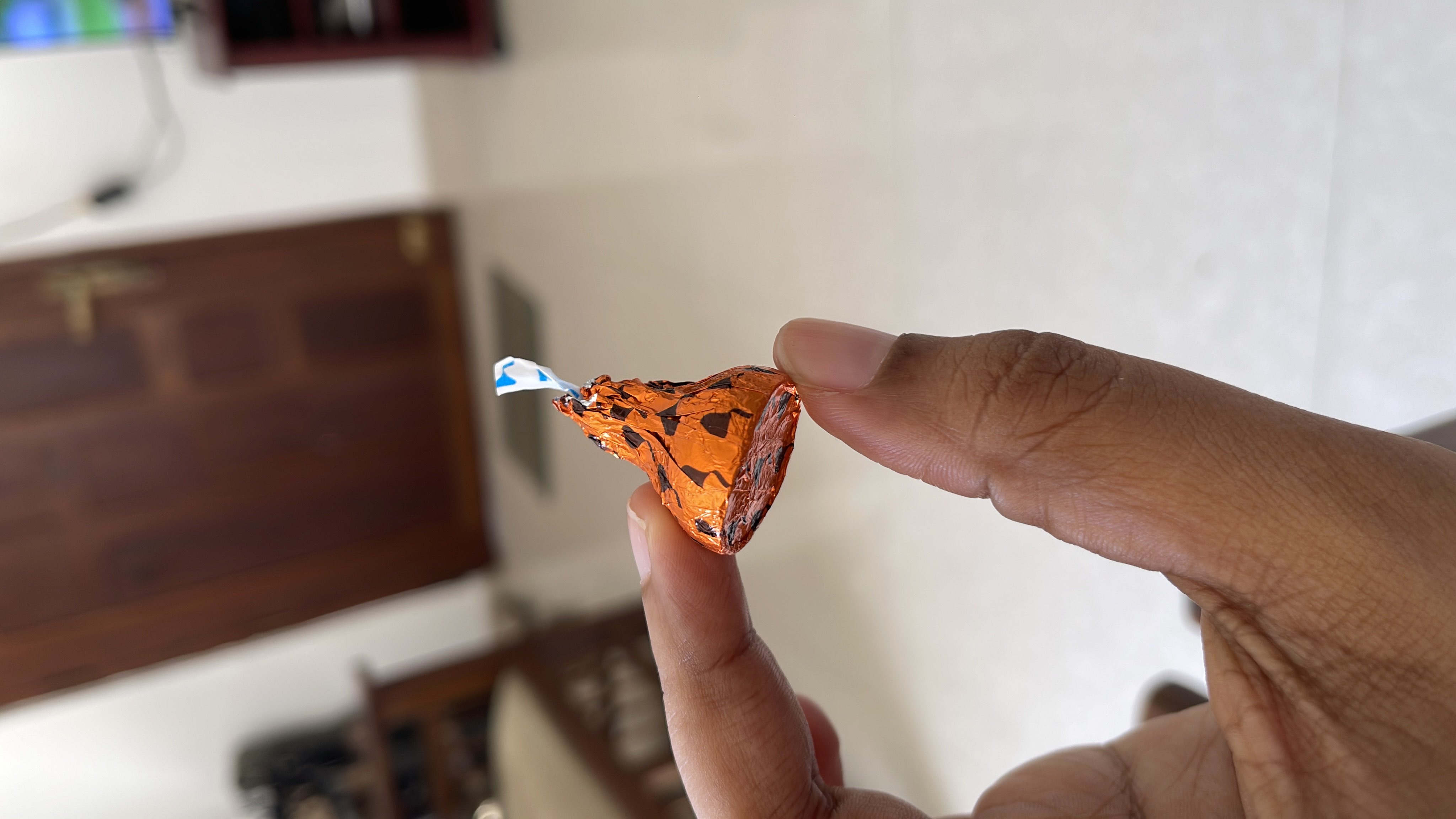 A small milk chocolate candy, wrapped in orange foil, typically consumed as a sweet treat.