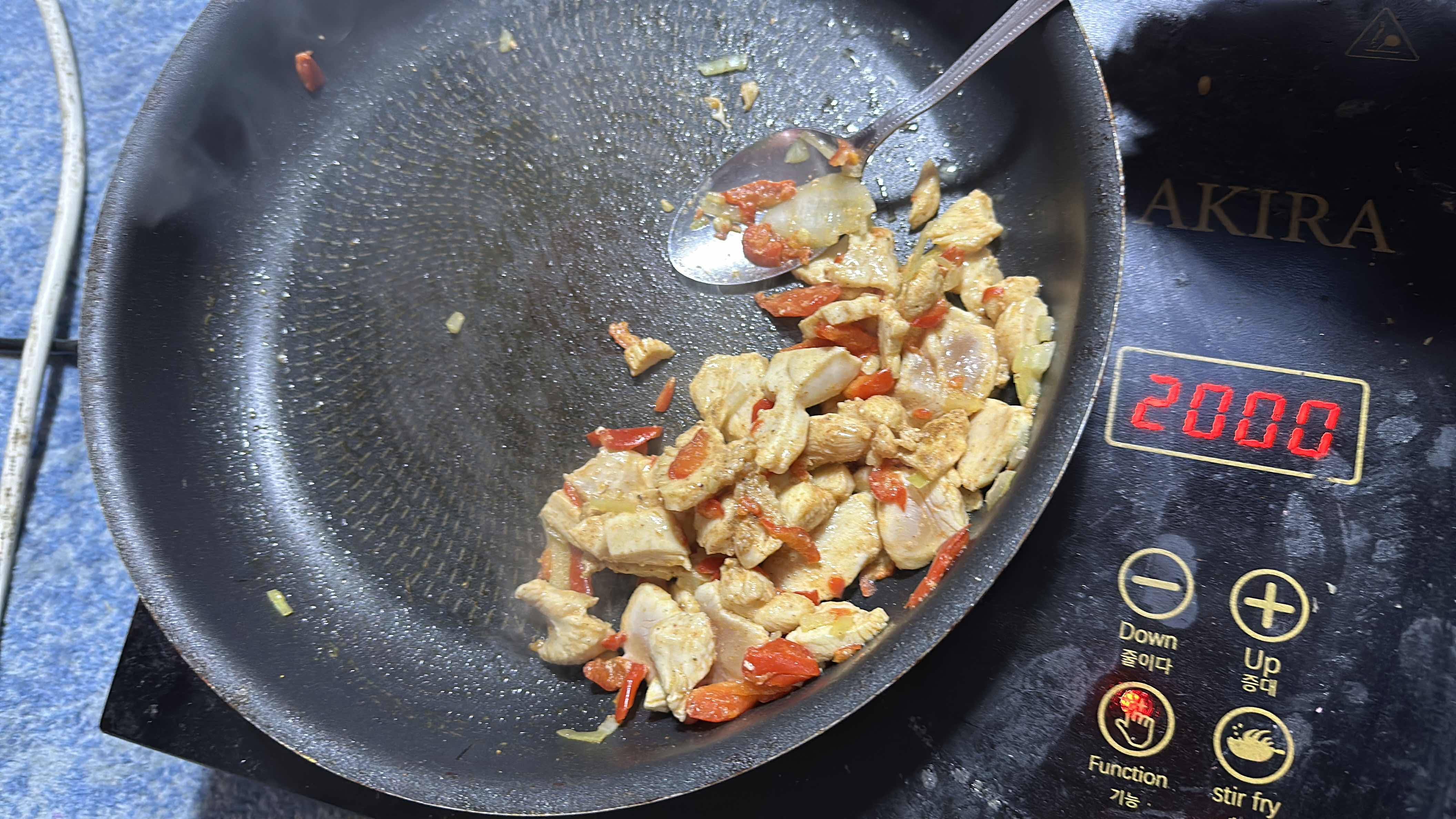 A stir-fried dish containing chicken, red bell peppers, and onions, cooked with minimal oil.