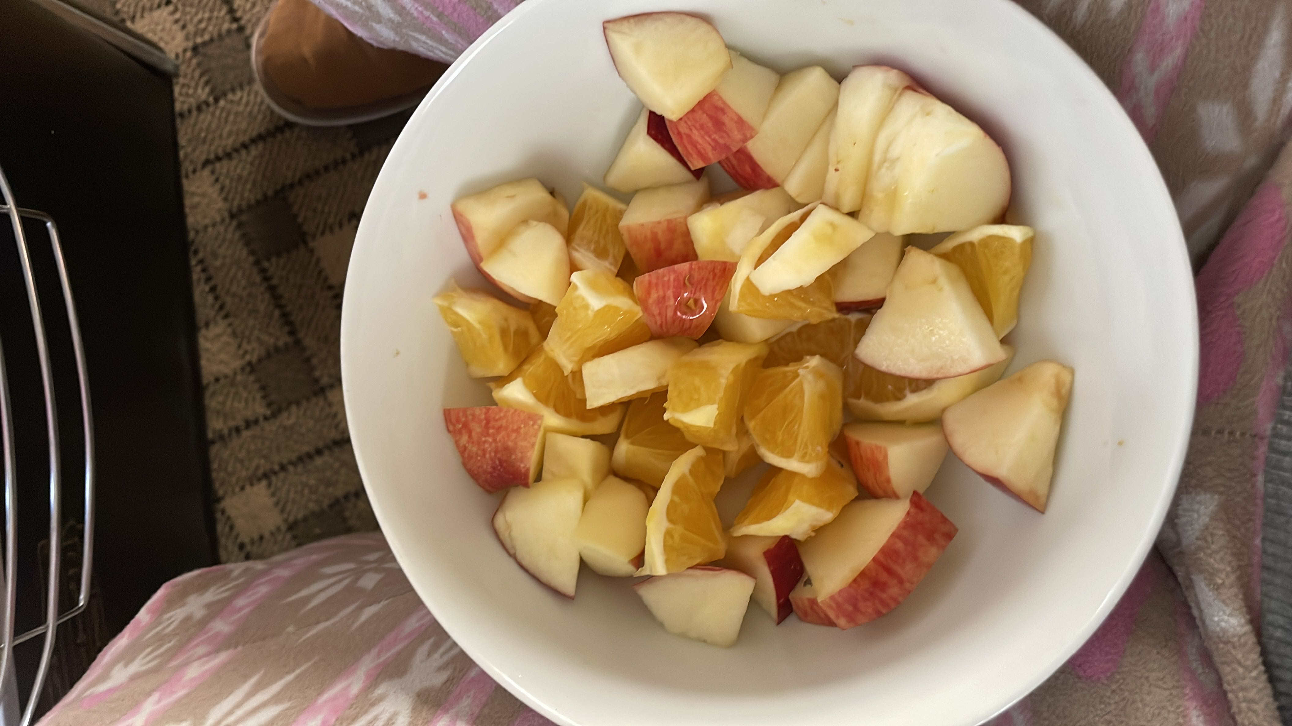 A bowl of fresh fruit salad containing chopped apples and oranges, providing a healthy and low-calorie snack.