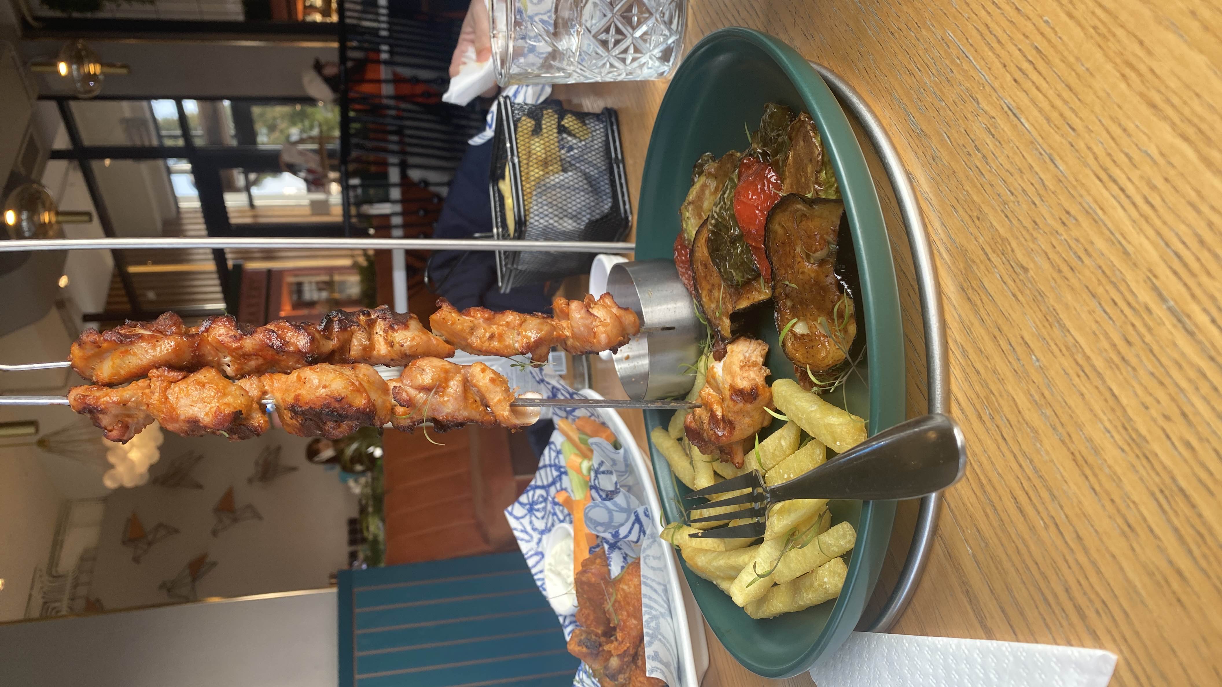 A dish featuring grilled chicken skewers, fried potatoes, and grilled vegetables, offering a balanced mix of protein, carbs, and fats.