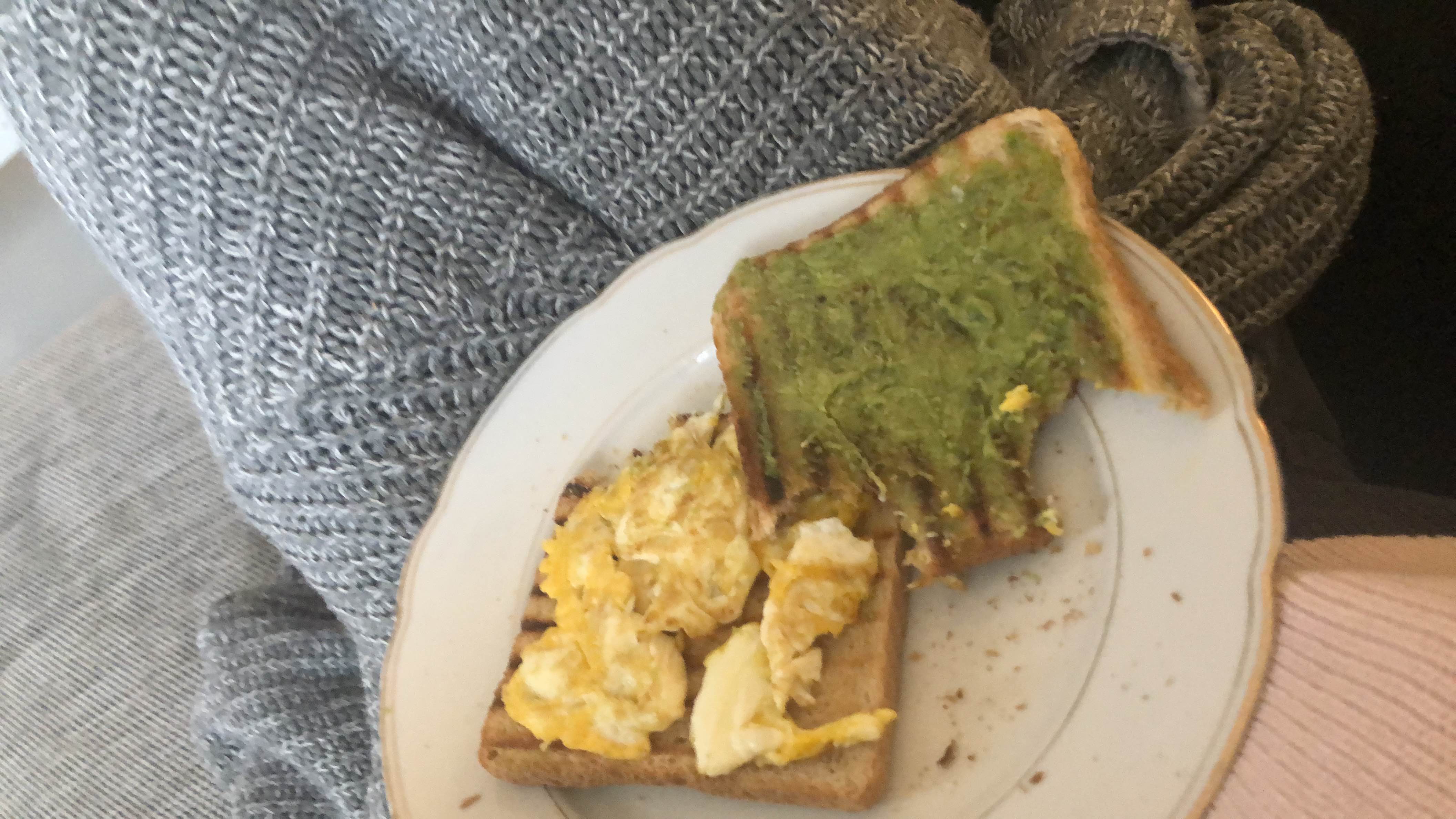 A plate with two slices of toast, one topped with scrambled eggs and the other with mashed avocado, providing a balanced mix of protein, healthy fats, and carbohydrates.