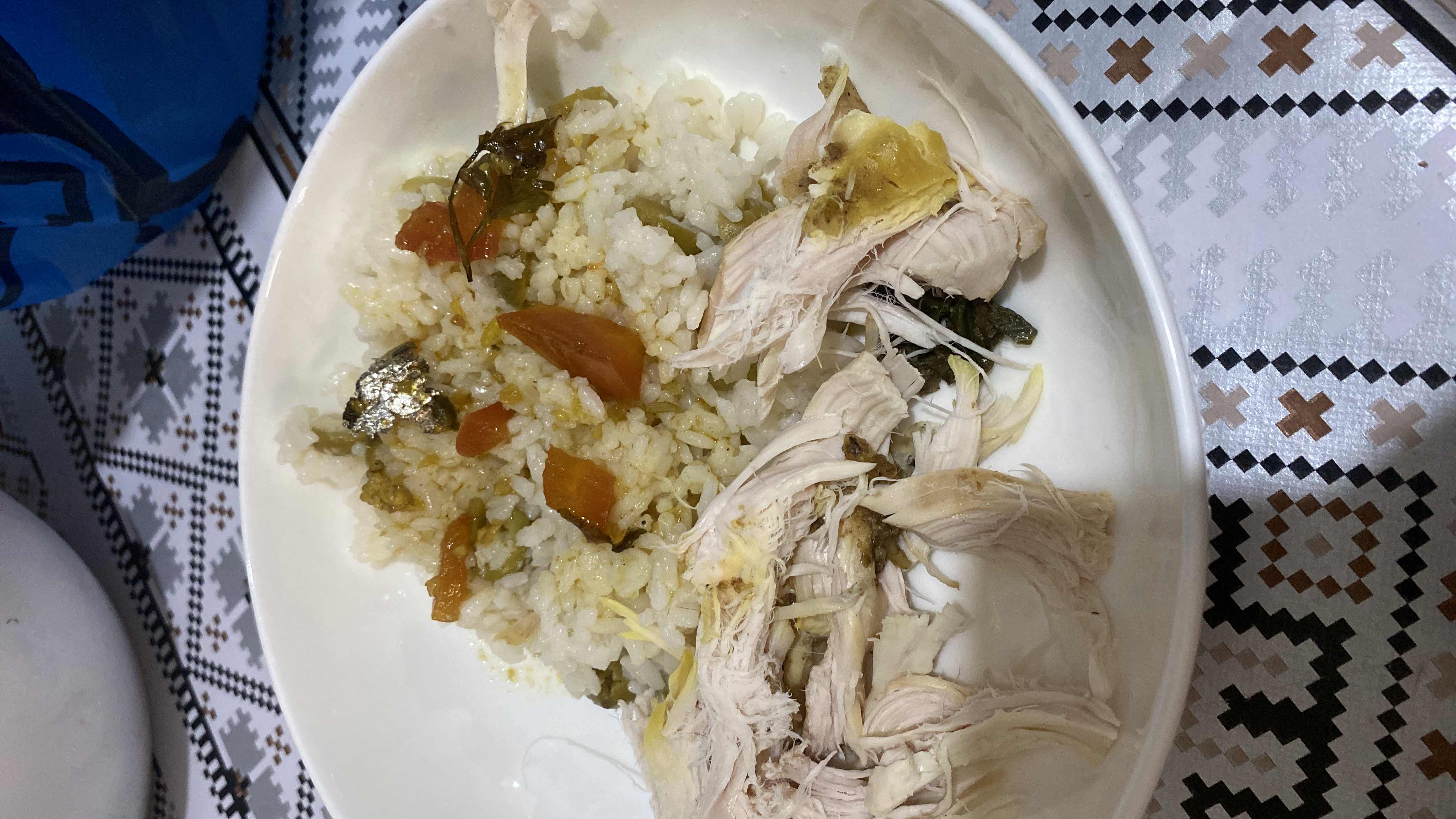 A dish consisting of steamed rice, shredded chicken, and cooked vegetables, providing a balanced mix of protein, carbohydrates, and fats.