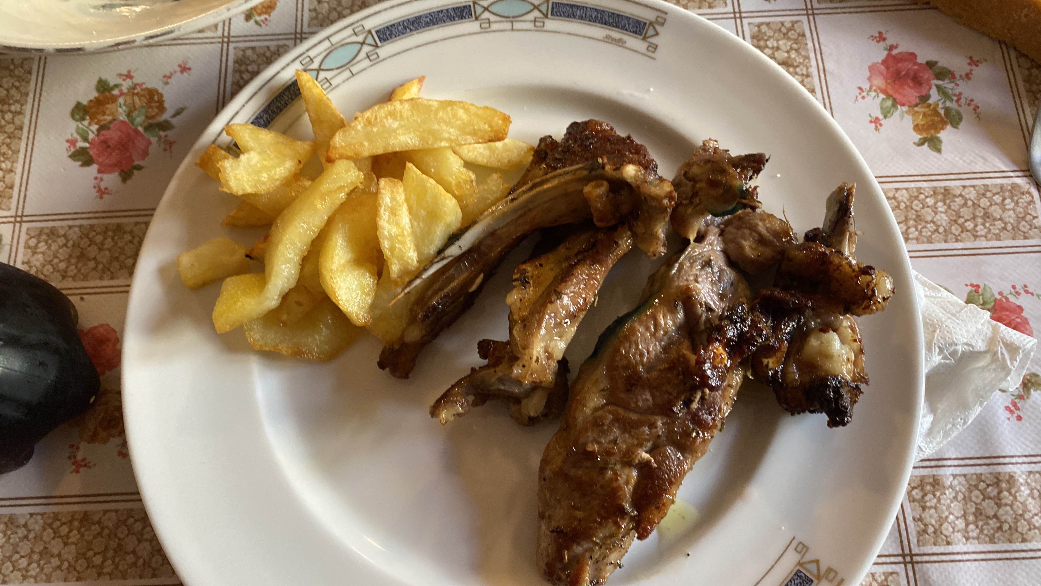 A plate containing grilled lamb chops and French fries, providing a balanced mix of protein, fats, and carbohydrates.