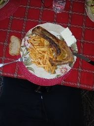 A meal consisting of grilled fish, french fries, bread, and a small portion of cheese.