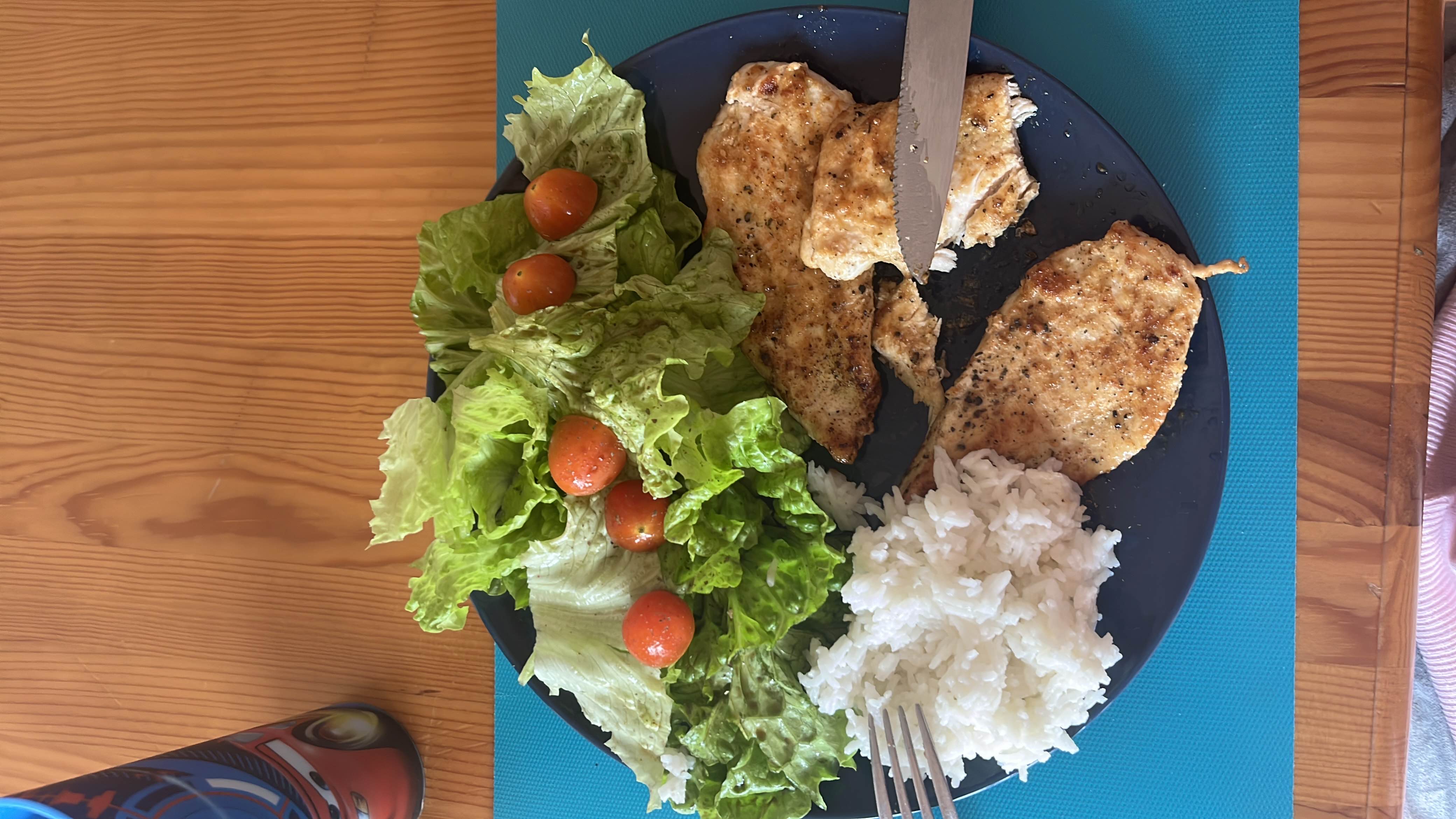 A balanced meal consisting of grilled chicken, white rice, fresh lettuce, cherry tomatoes, and a light olive oil dressing.