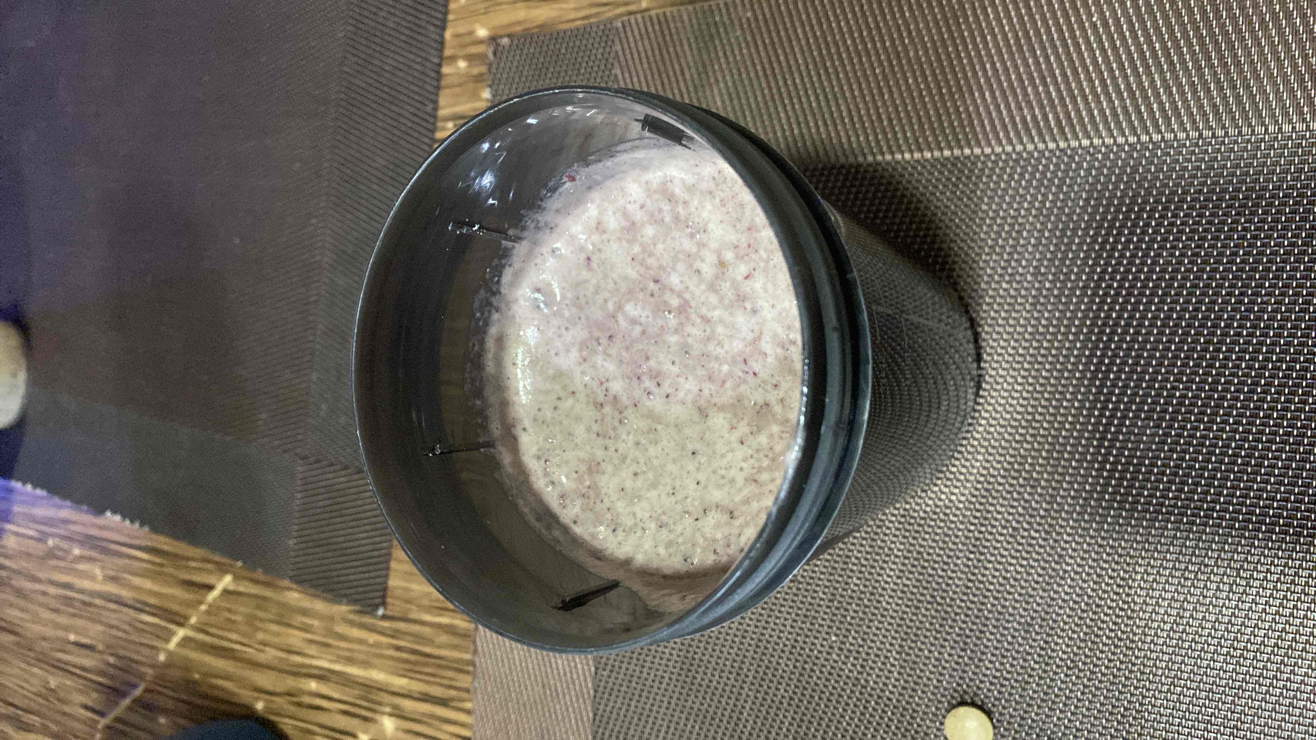 A protein shake made with protein powder, blueberries, spinach, and flaxseed, providing a balanced mix of protein, carbs, and fats.