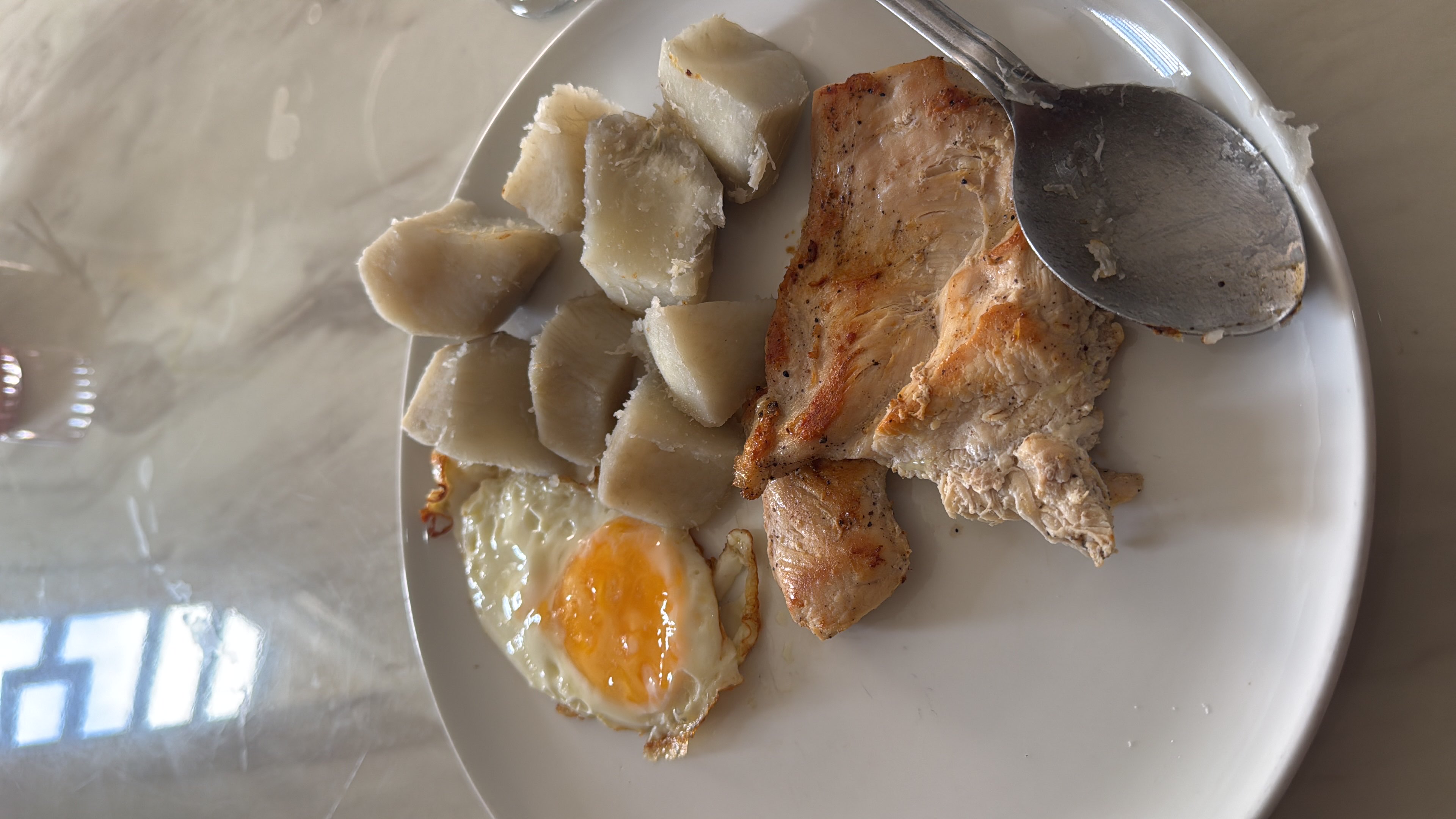 A balanced meal consisting of boiled yam, a fried egg, and grilled chicken breast, providing a good mix of protein, carbohydrates, and fats.