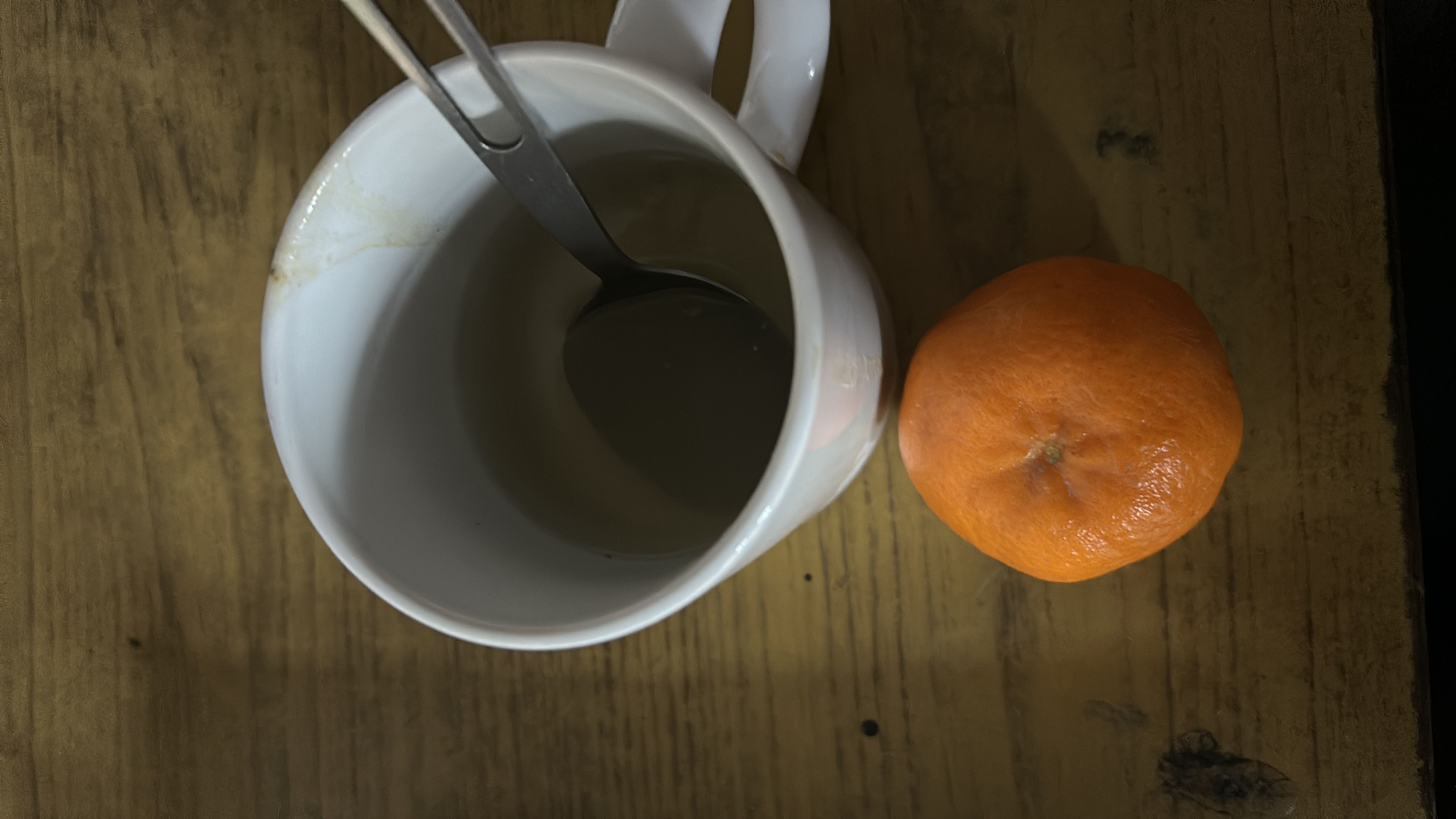 A cup of green tea and a mandarin orange, providing a low-calorie and nutritious snack.