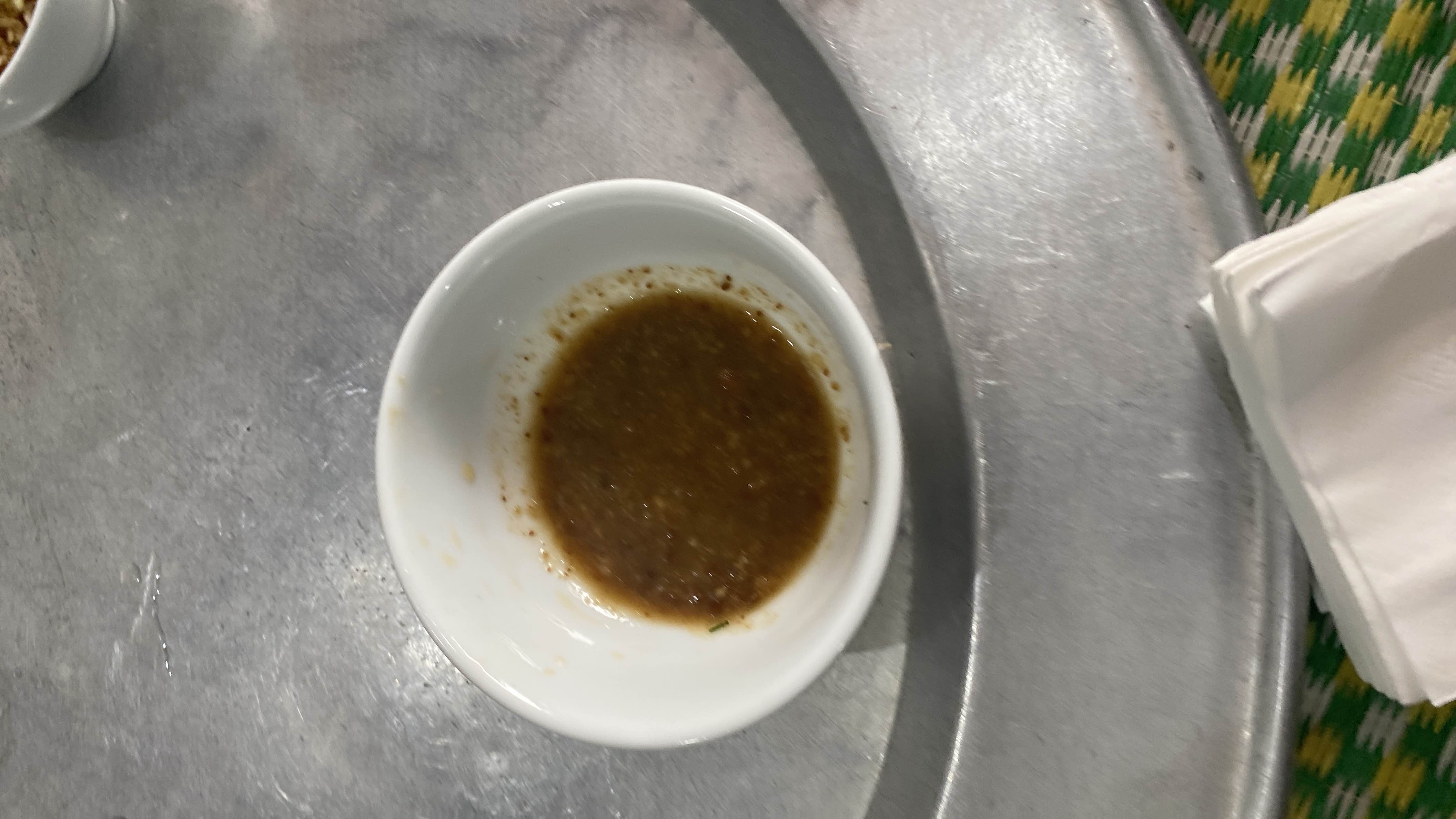 A small portion of a light, savory sauce, likely used as a condiment or dip.