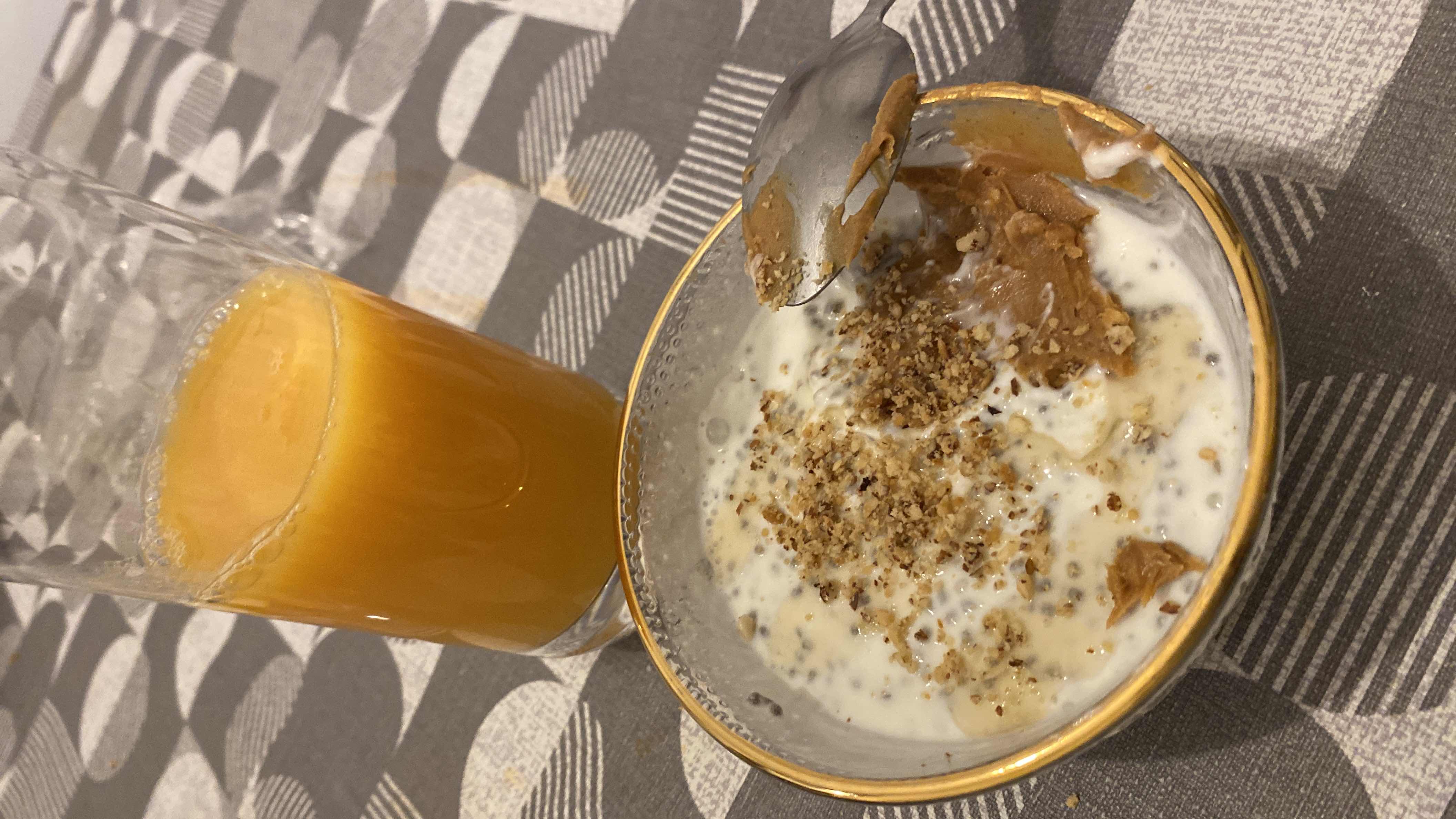 A nutritious breakfast bowl with yogurt, peanut butter, granola, chia seeds, and a glass of orange juice.