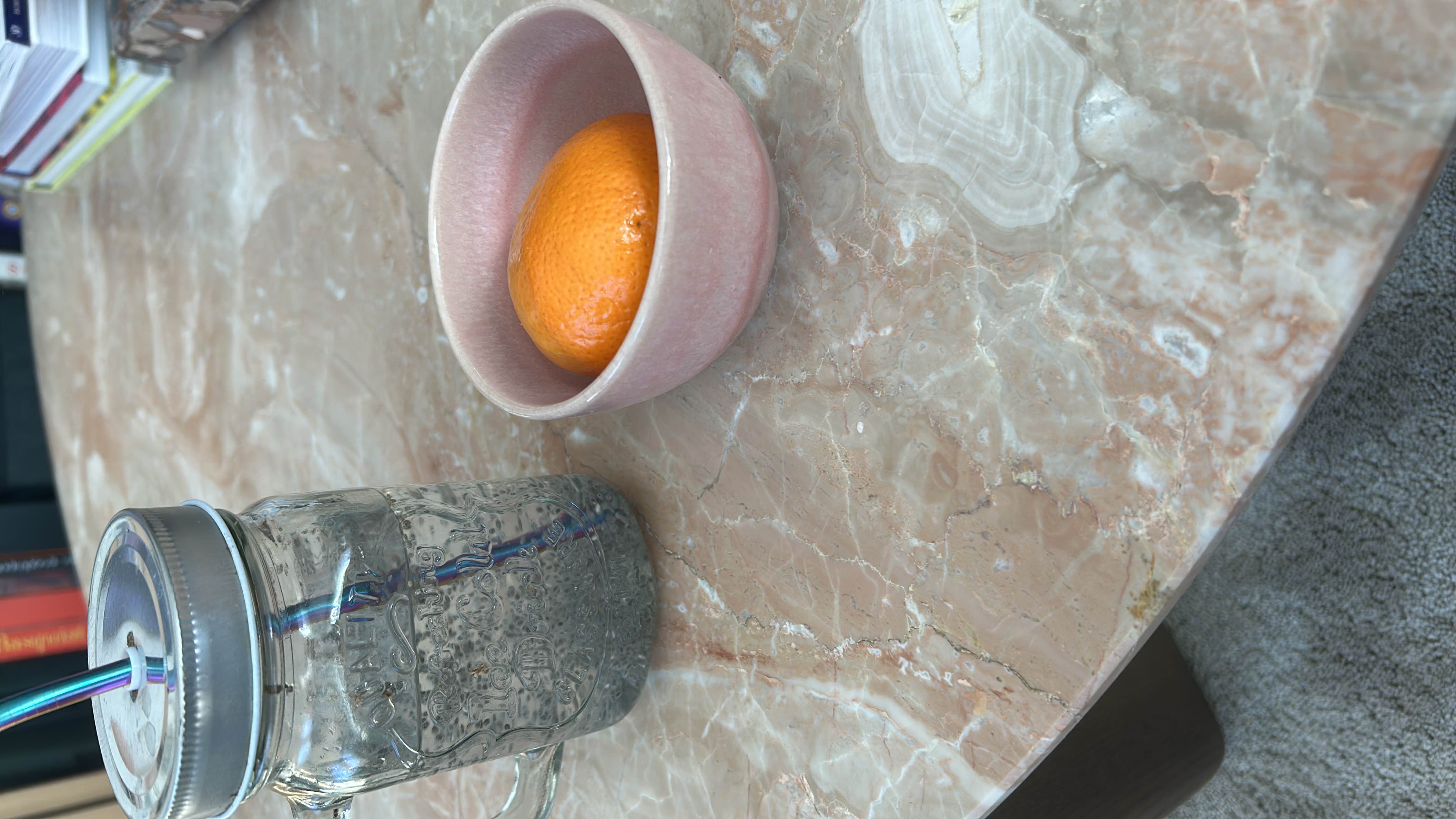The image shows a glass of water and a bowl containing an orange, which is a low-calorie, nutrient-rich fruit.