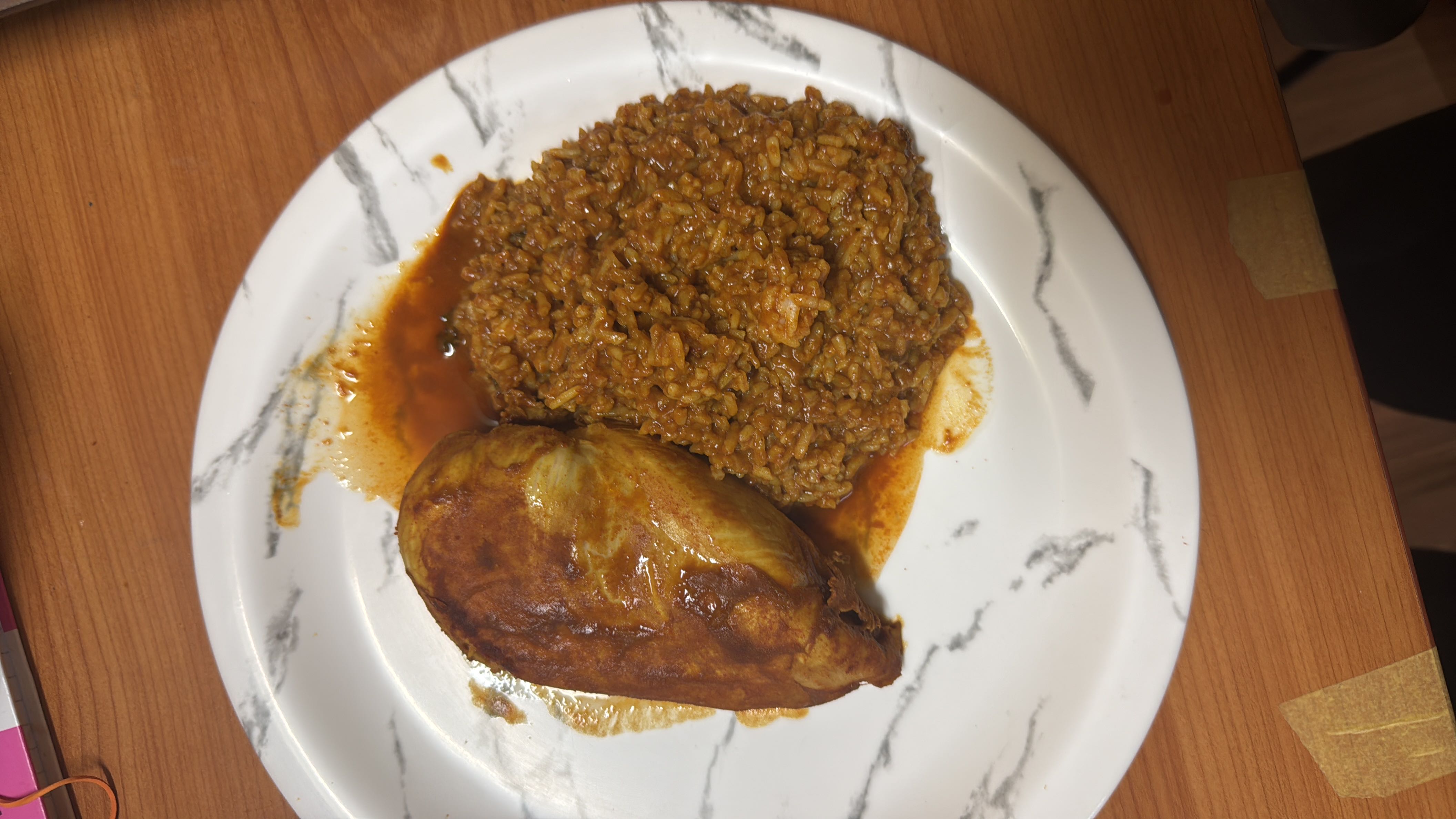 A plate containing a grilled chicken breast and a serving of seasoned rice, providing a balanced mix of protein, carbs, and fats.
