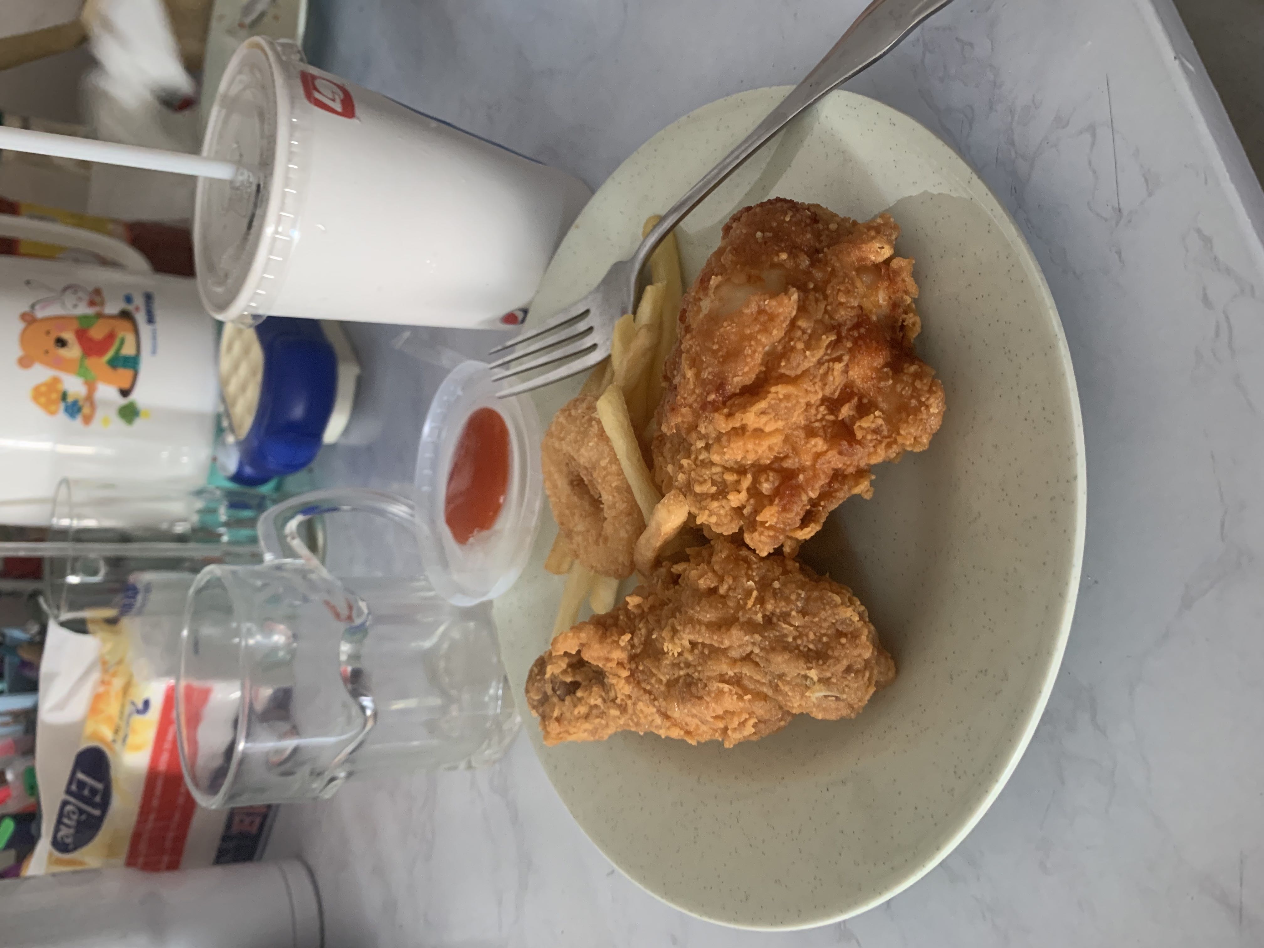 A meal consisting of fried chicken, french fries, onion rings, and a soft drink.
