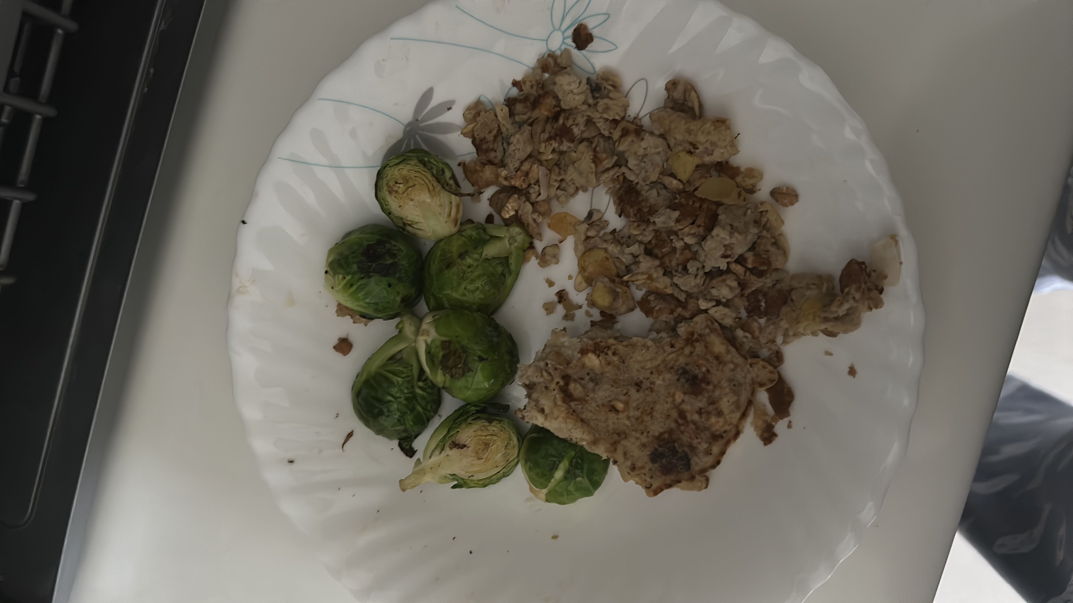 A plate containing Brussels sprouts, scrambled eggs, and a vegetable patty, providing a balanced mix of protein, carbs, and fats.
