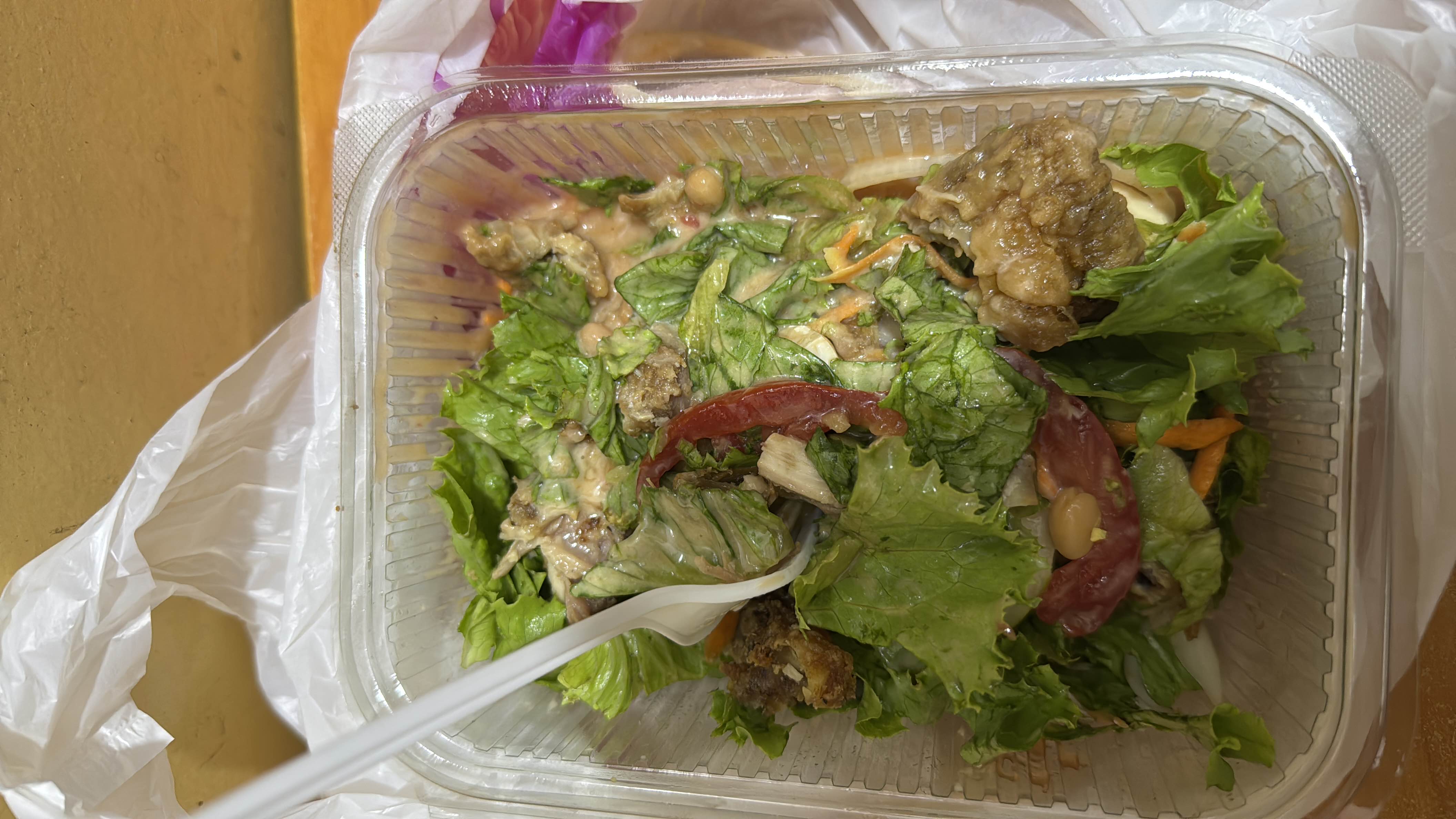 A healthy salad with lettuce, tomato, chickpeas, grilled chicken, and dressing.