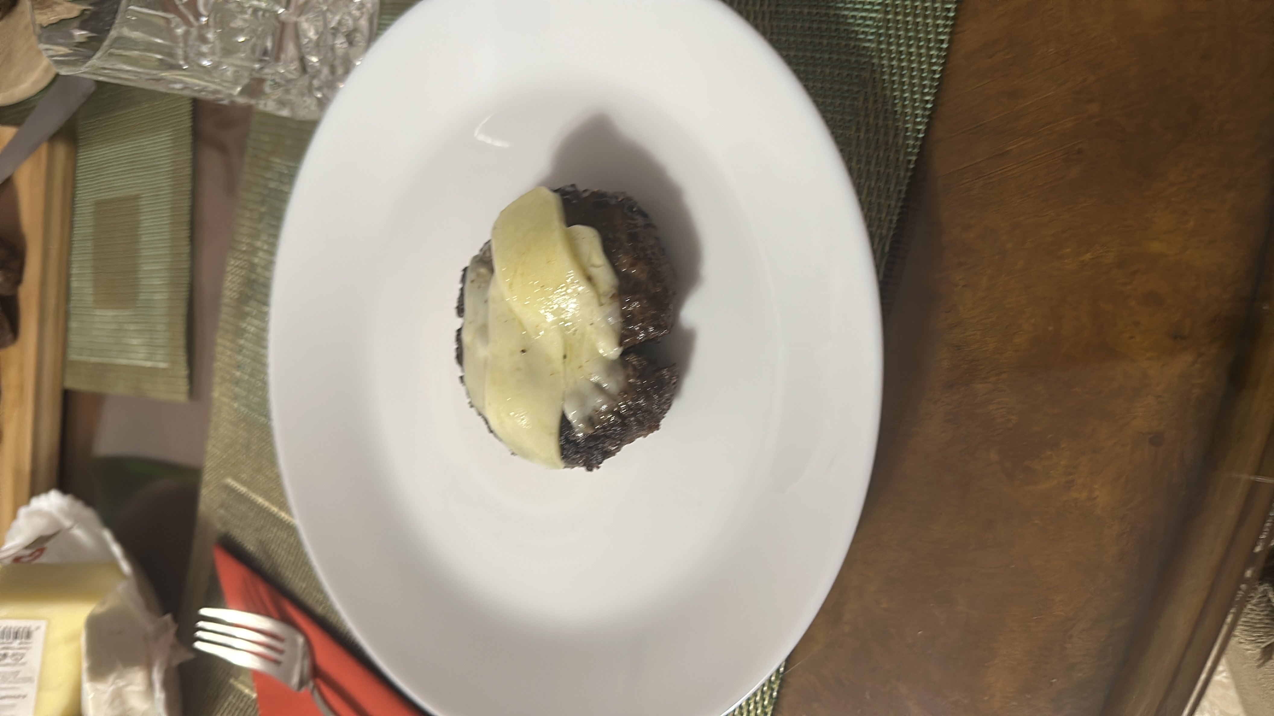 A 1.5x serving of a beef patty topped with melted cheese, served on a white plate.