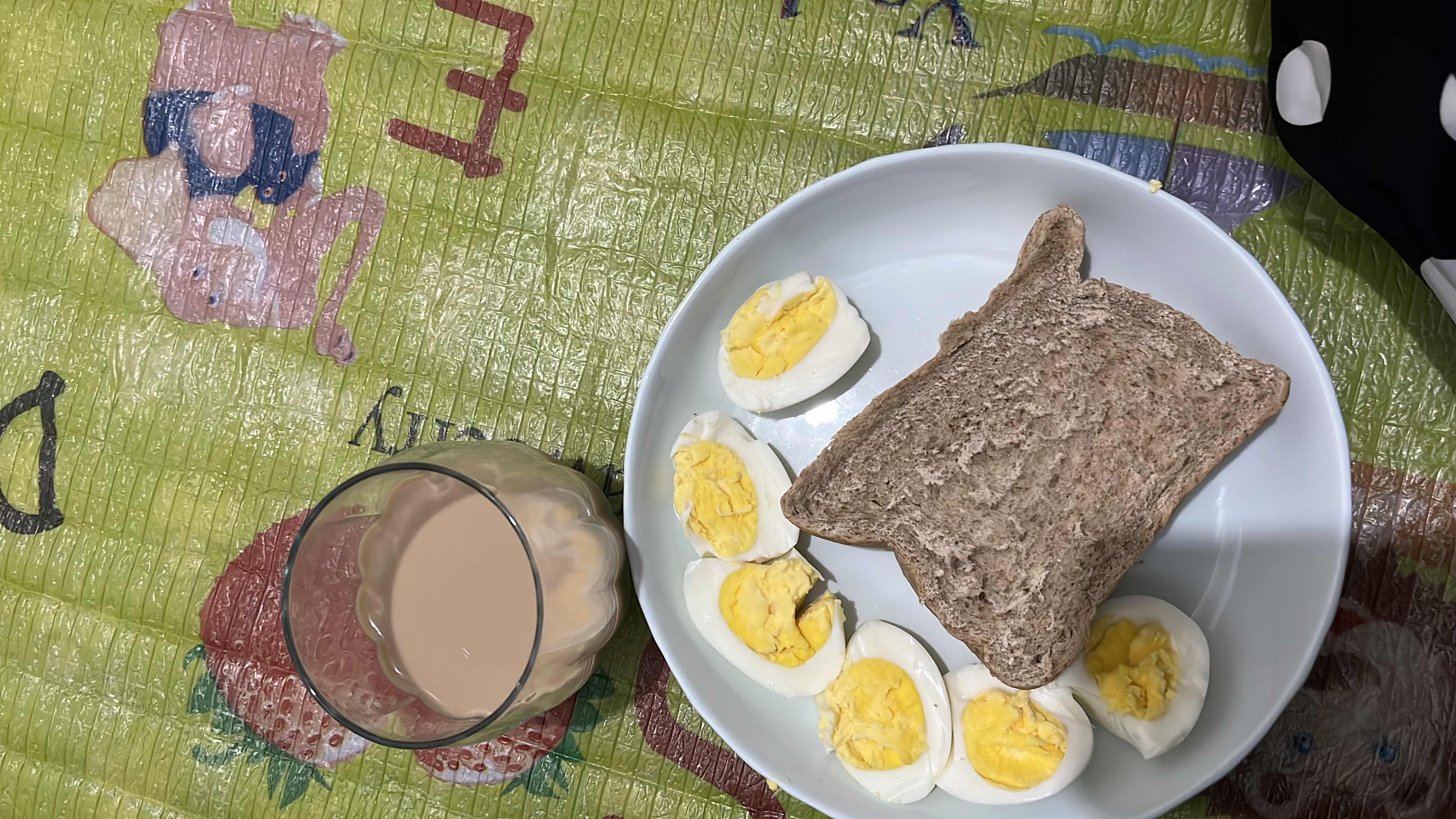 A balanced meal consisting of boiled eggs, whole grain bread, and milk tea, providing a good mix of protein, carbs, and fats.
