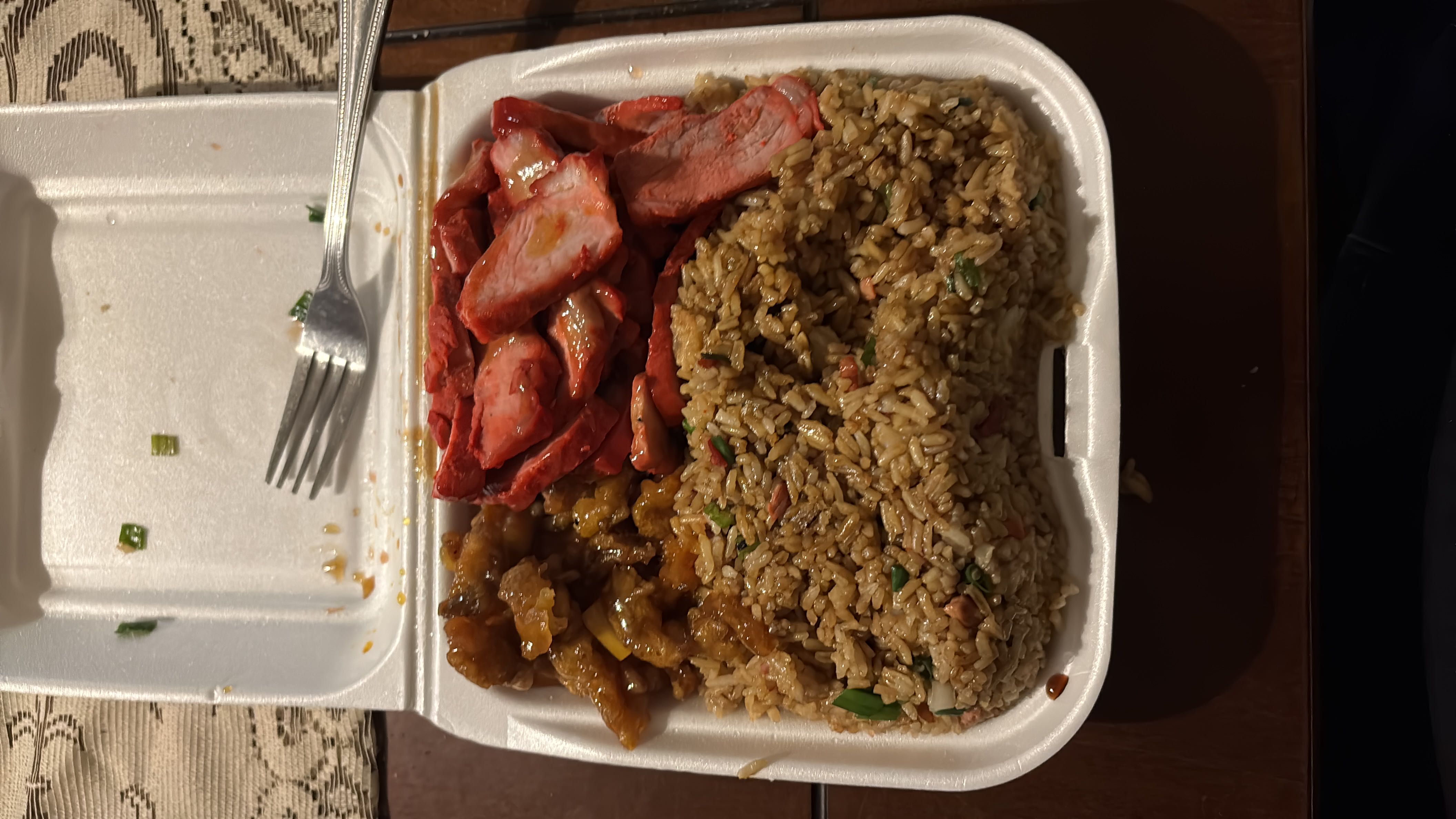 A takeout meal consisting of fried rice, orange chicken, and char siu pork, providing a balanced mix of protein, carbs, and fats.