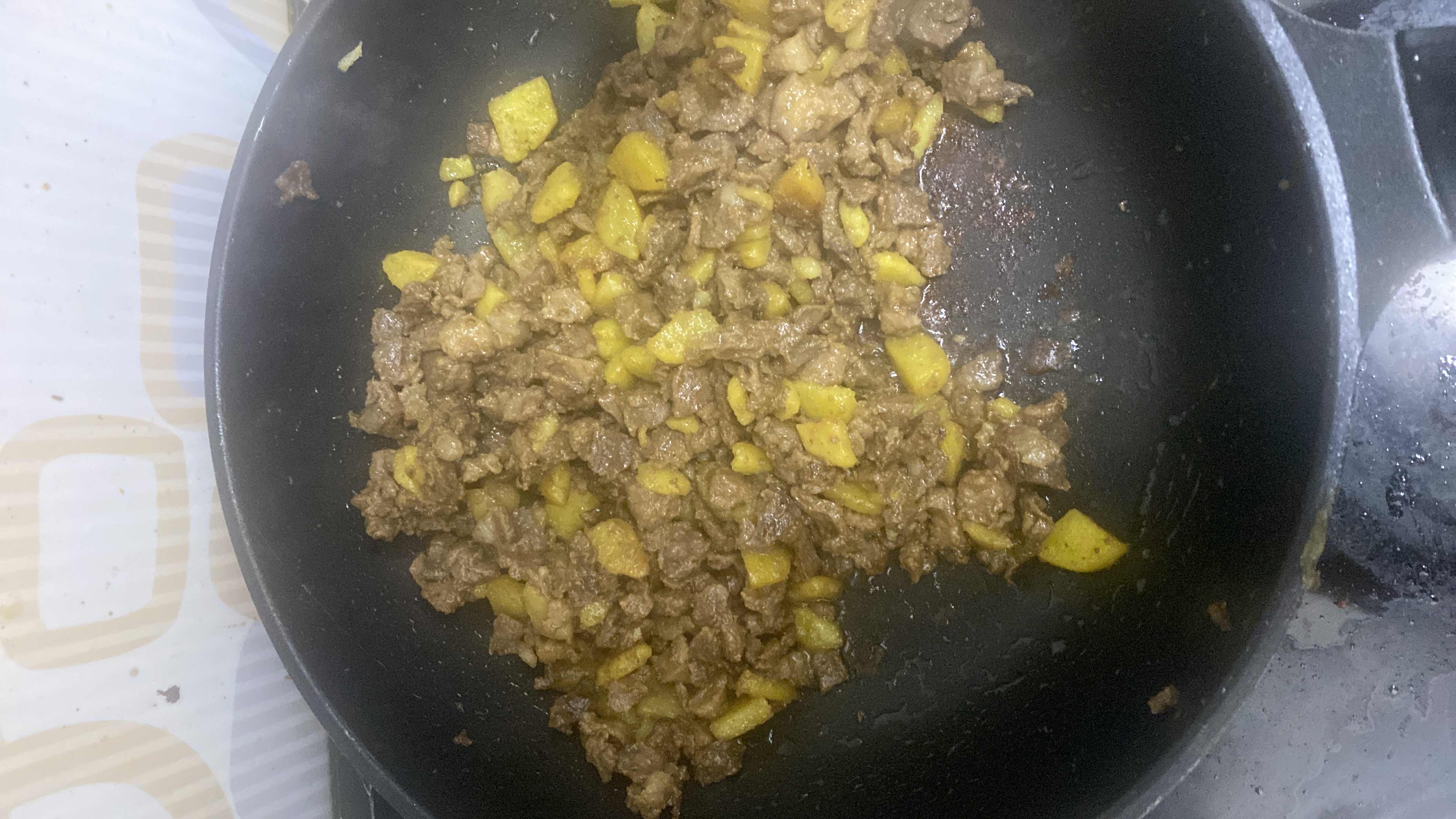 A dish consisting of cooked beef and diced potatoes, likely seasoned and sautéed.