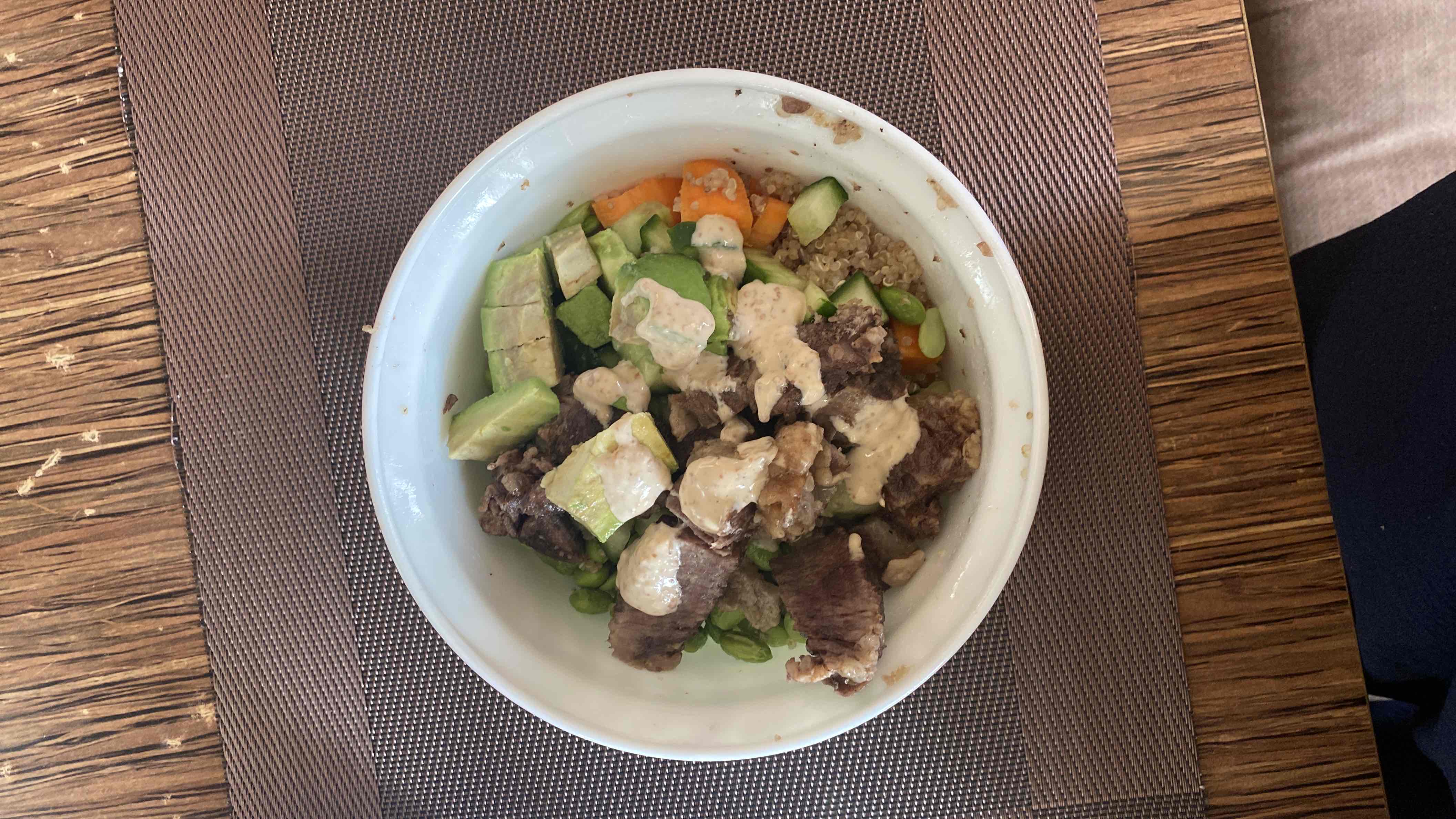 A nutritious bowl containing 81g beef, 26g avocado, 100g quinoa, 65g cucumber, 53g carrot, and 86g edamame, topped with a creamy dressing.