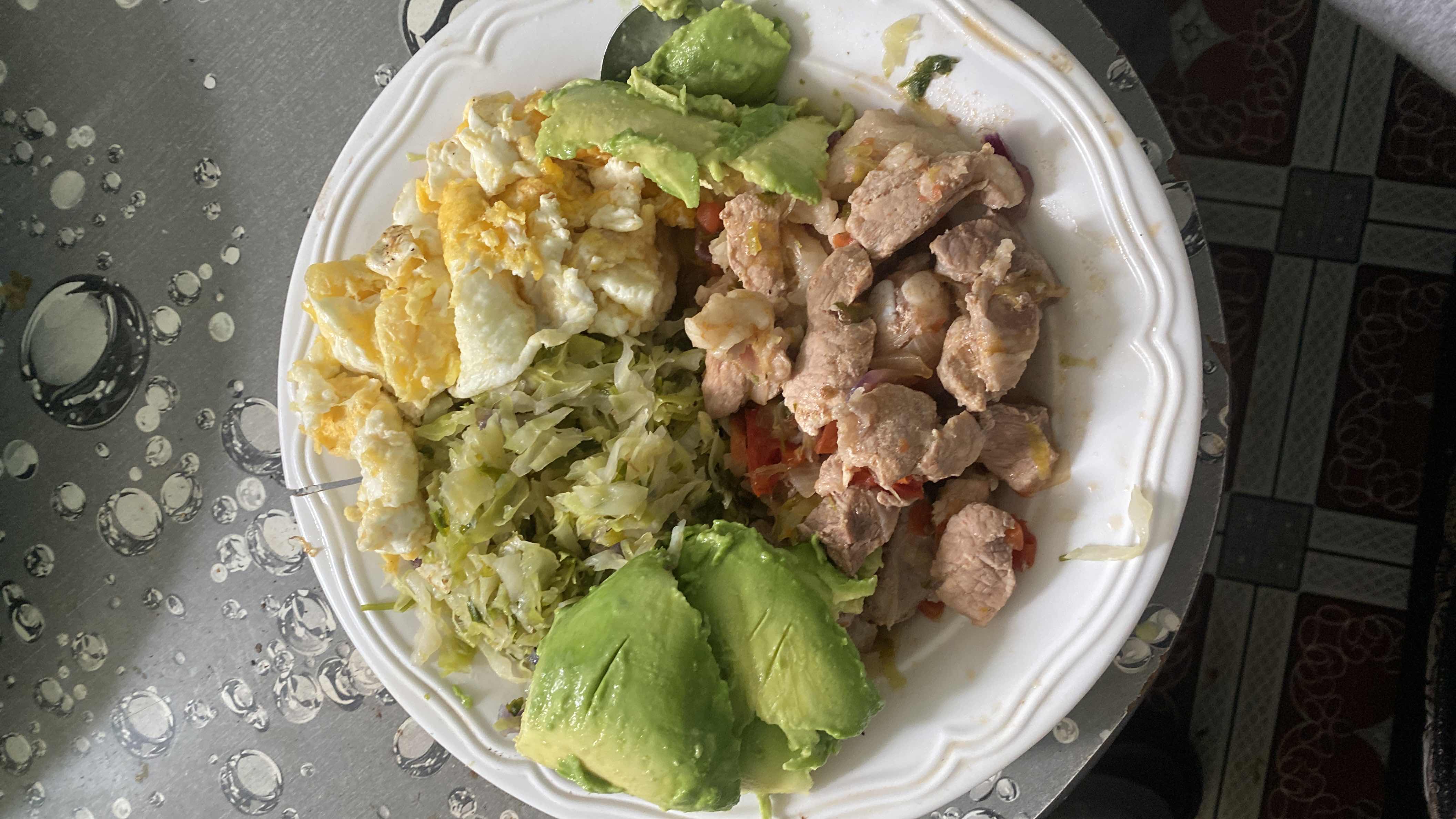 A balanced meal consisting of avocado slices, scrambled eggs, cooked cabbage, and cooked meat, providing a good mix of protein, healthy fats, and moderate carbohydrates.