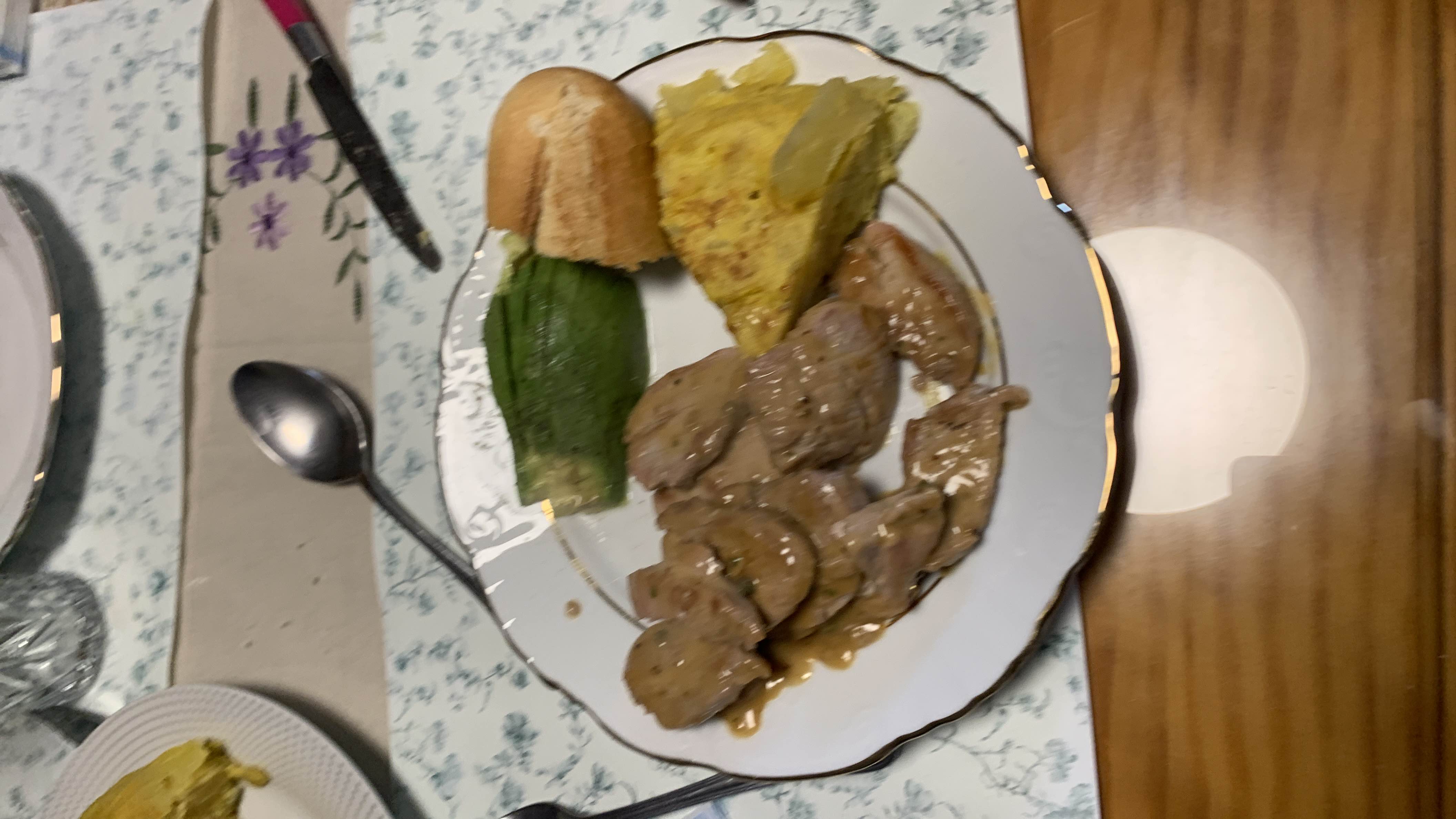 A balanced meal consisting of sirloin slices in sauce, avocado, bread, and a portion of potato omelette.