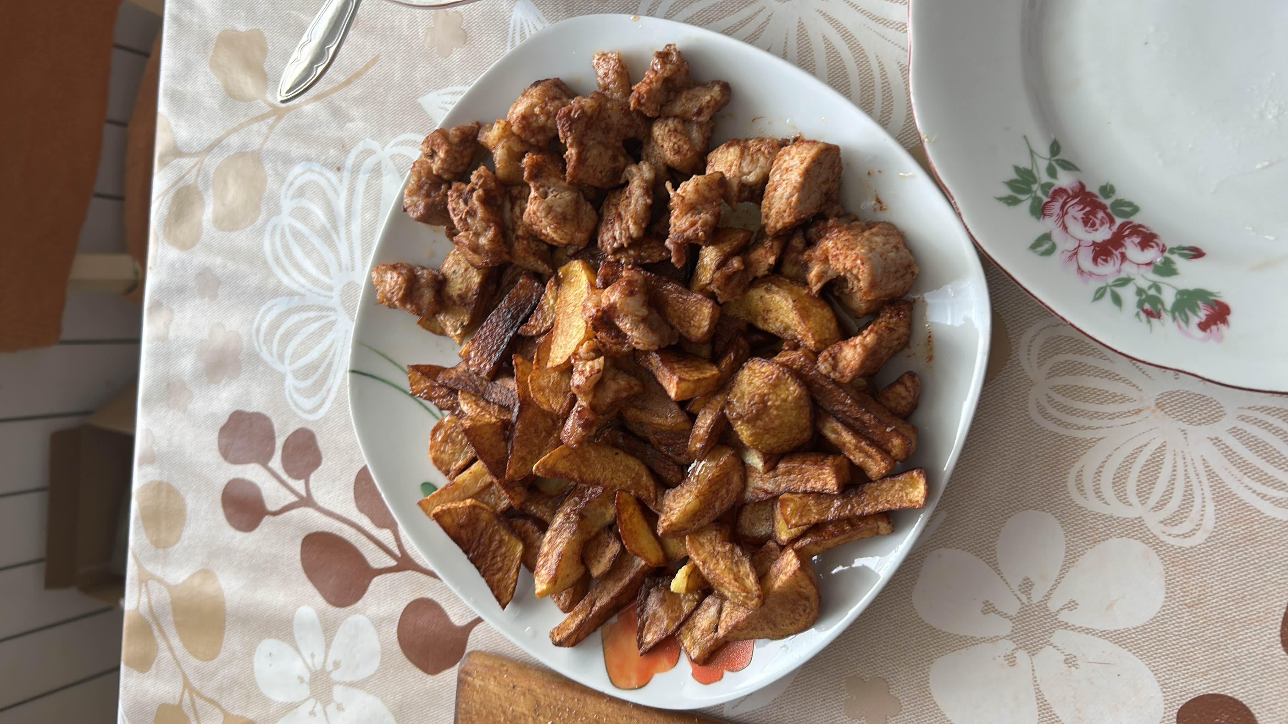 A dish consisting of fried potatoes and seasoned chicken pieces, likely prepared with oil.