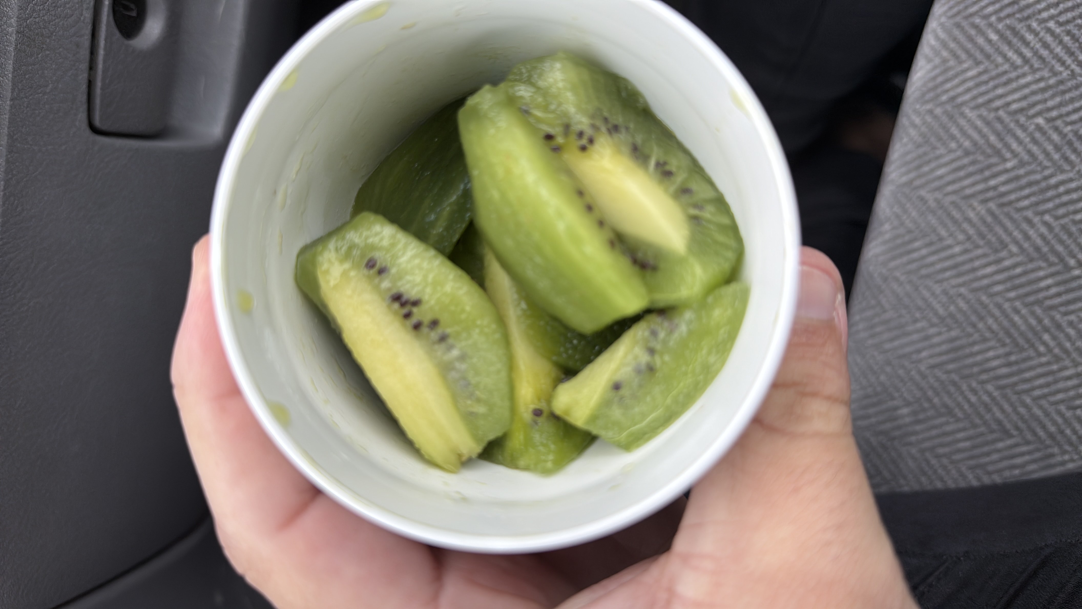 A cup containing sliced kiwi, a low-calorie fruit rich in vitamins and fiber.