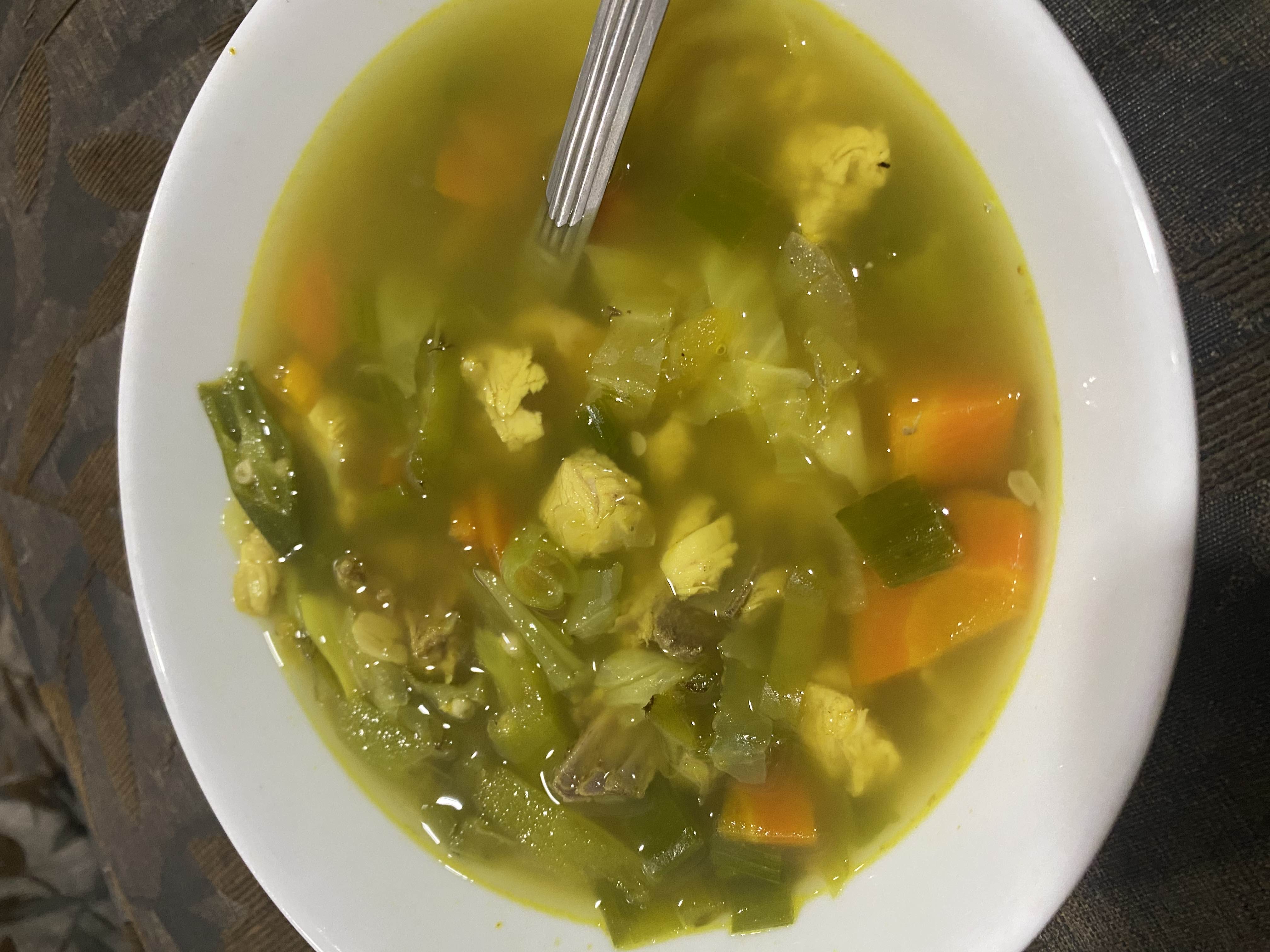 A healthy chicken and vegetable soup with carrots, green beans, cabbage, and a light broth.