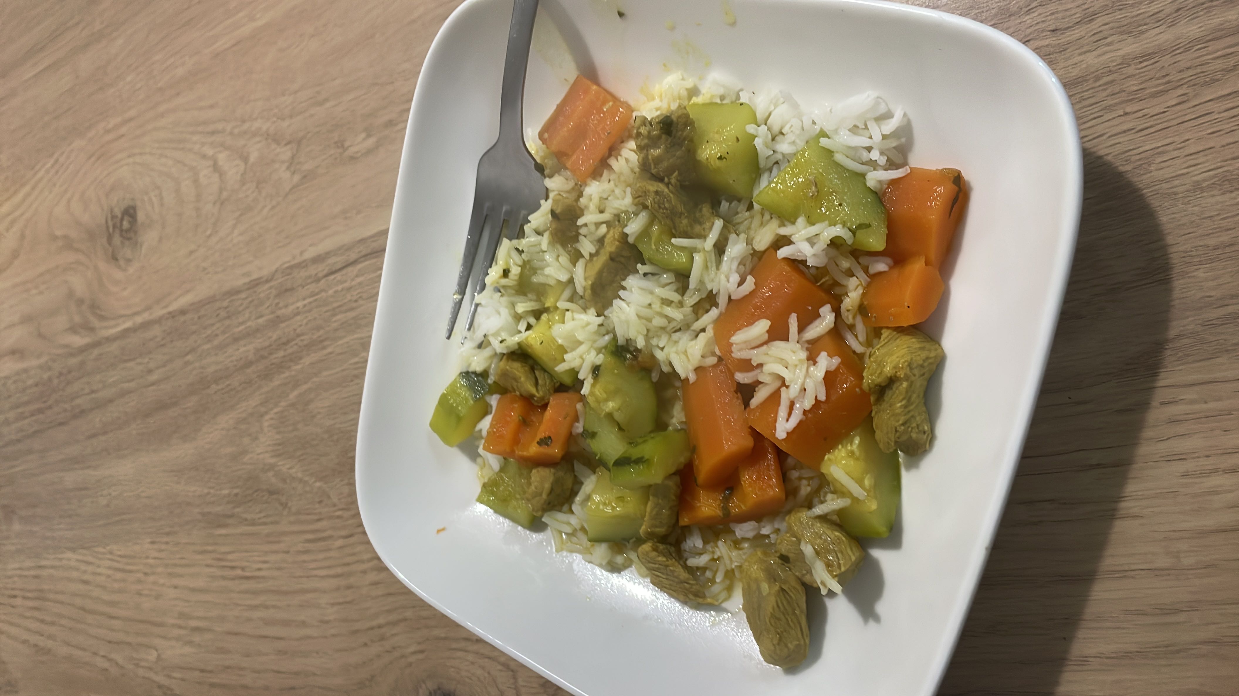 A balanced dish containing rice, chicken, and vegetables such as carrots and zucchini, providing a good mix of protein, carbs, and fats.