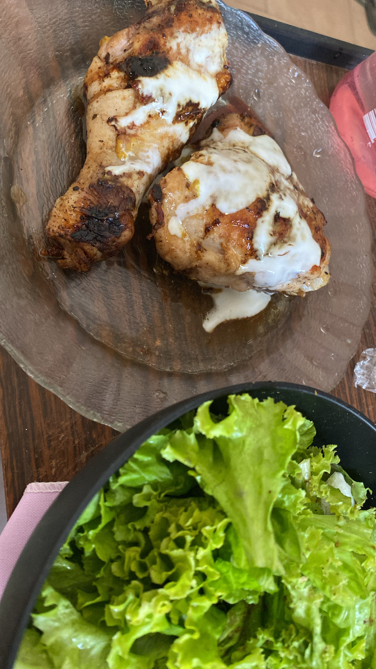 A meal consisting of grilled chicken with a creamy topping and a side of fresh lettuce.