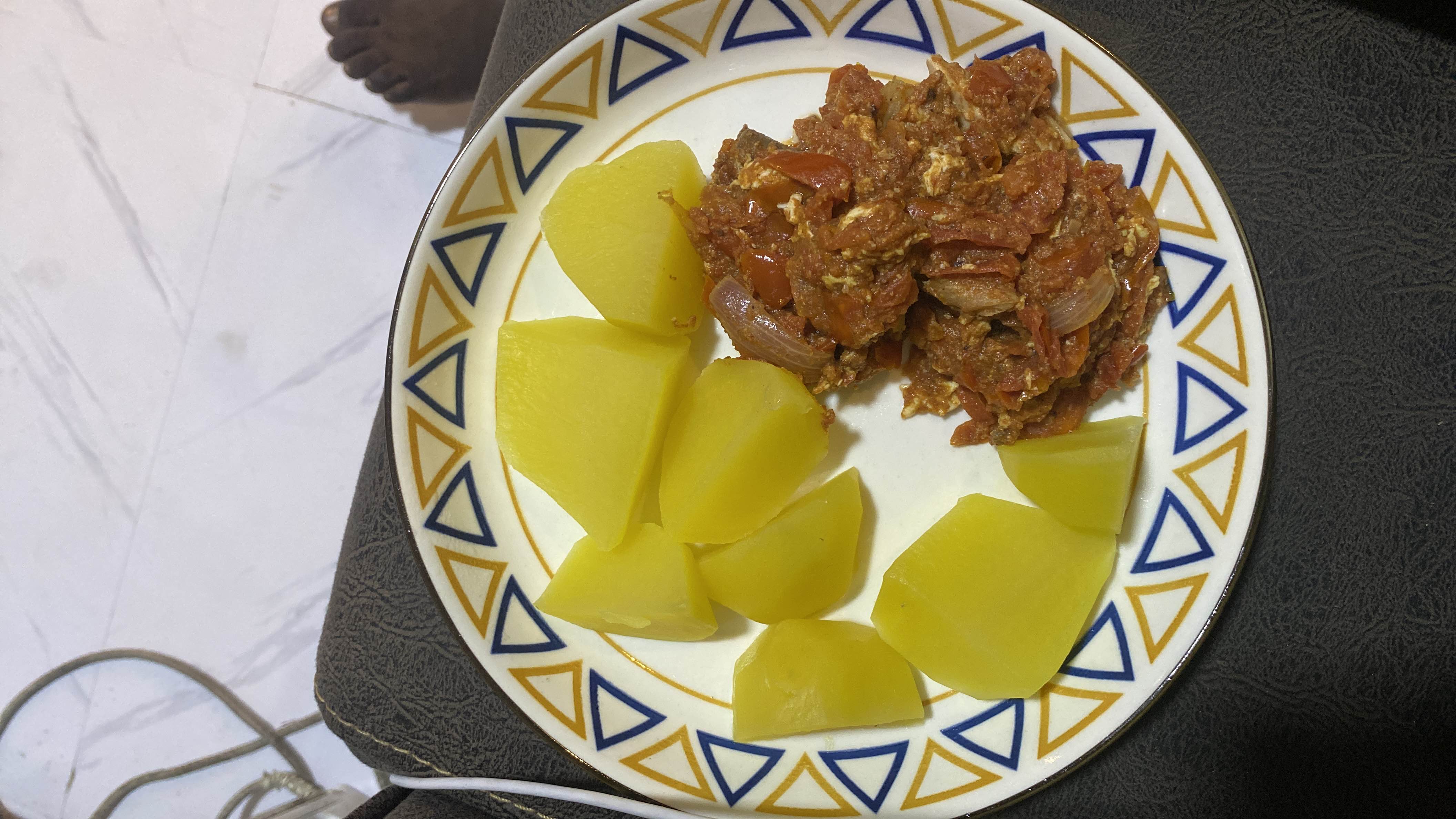 A plate of boiled potatoes served with tomato and egg sauce, providing a balanced mix of carbohydrates, protein, and fats.