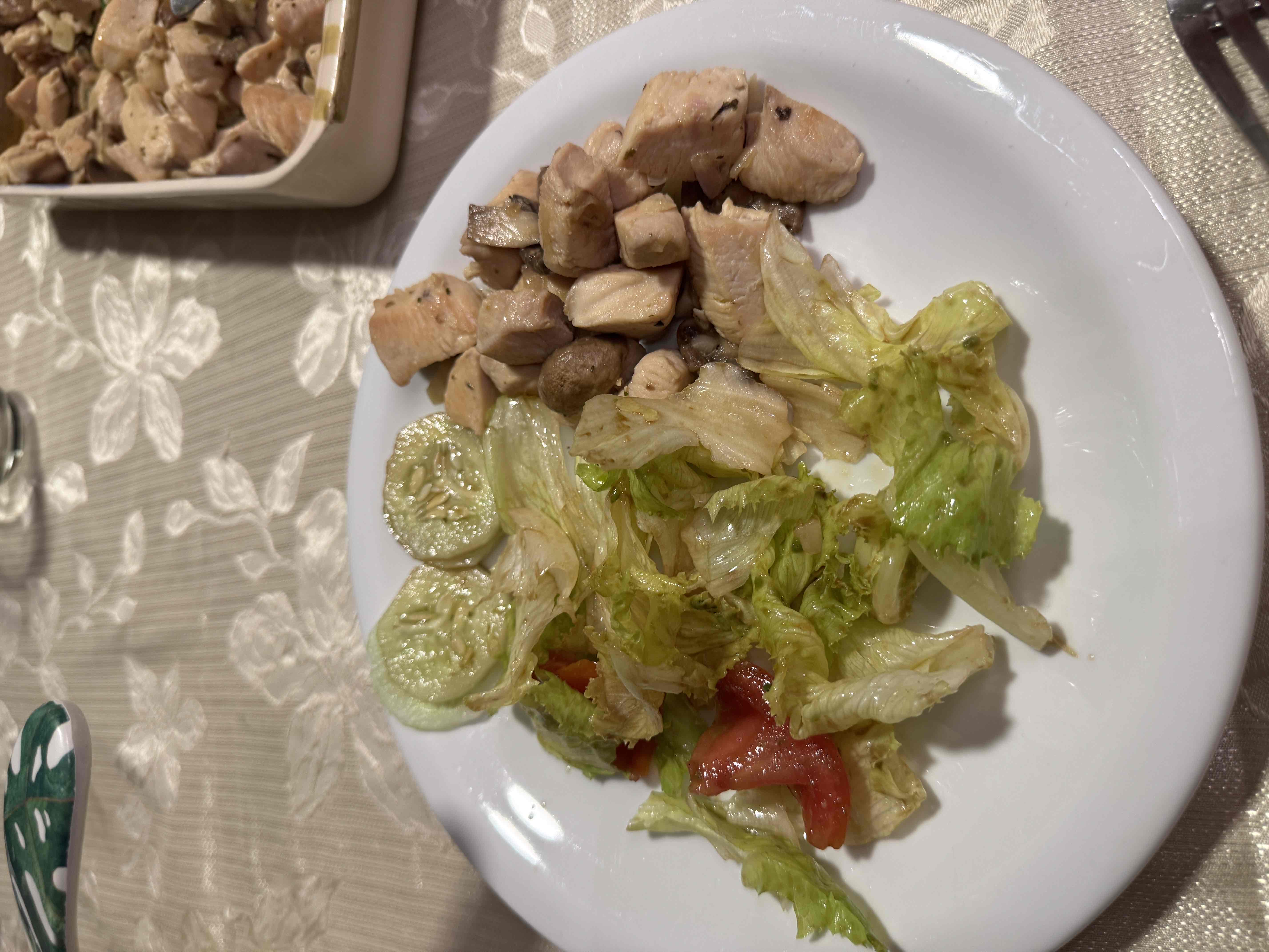 A healthy dish consisting of grilled chicken, lettuce, cucumber, tomato, and a light drizzle of olive oil.
