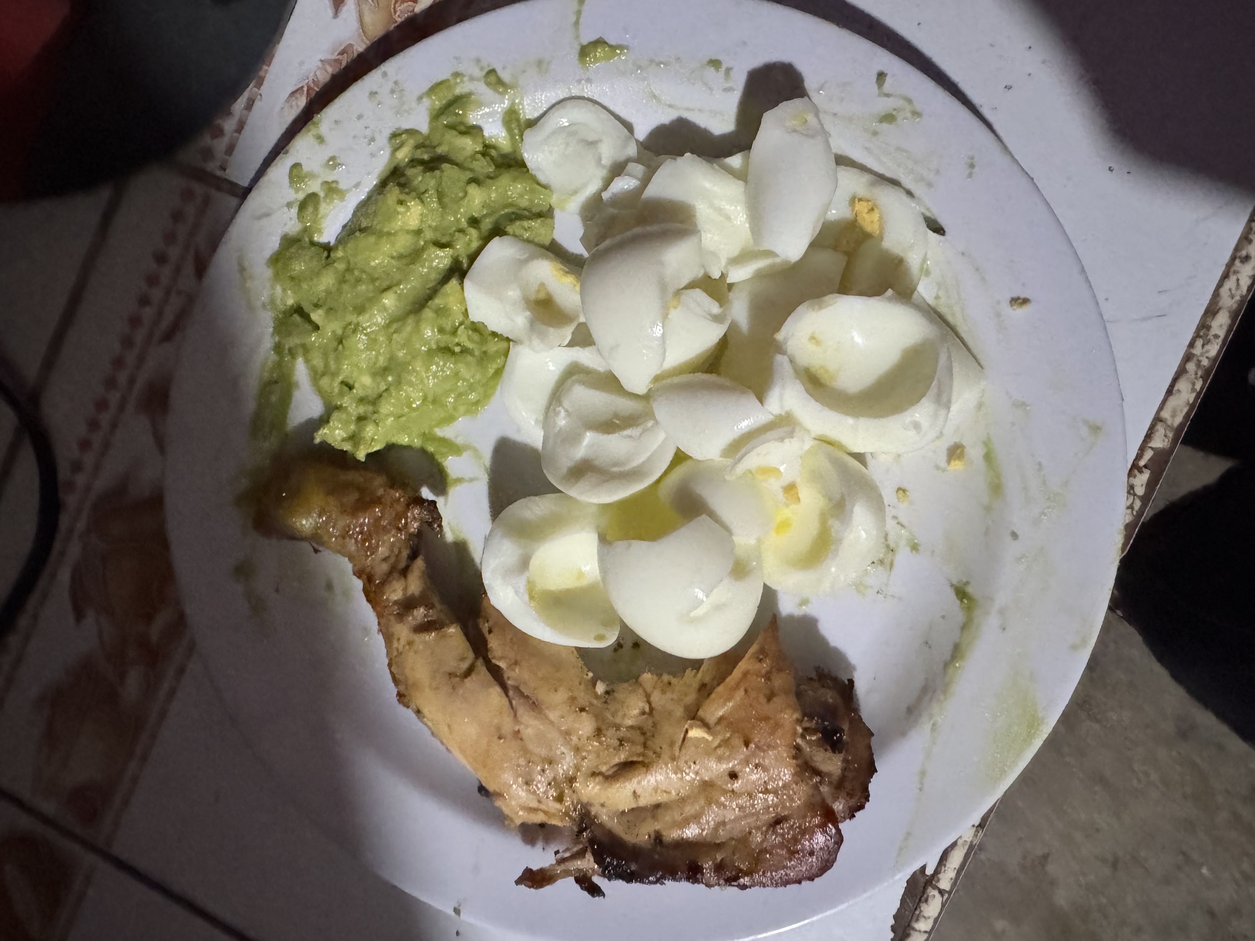 A plate containing grilled chicken, boiled eggs, and guacamole, providing a high-protein, low-carb meal.