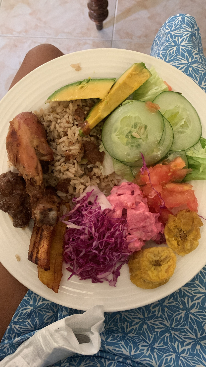 A balanced meal consisting of chicken, rice, plantains, avocado, cabbage, beet salad, cucumber, and tomato, providing a mix of protein, carbs, and healthy fats.