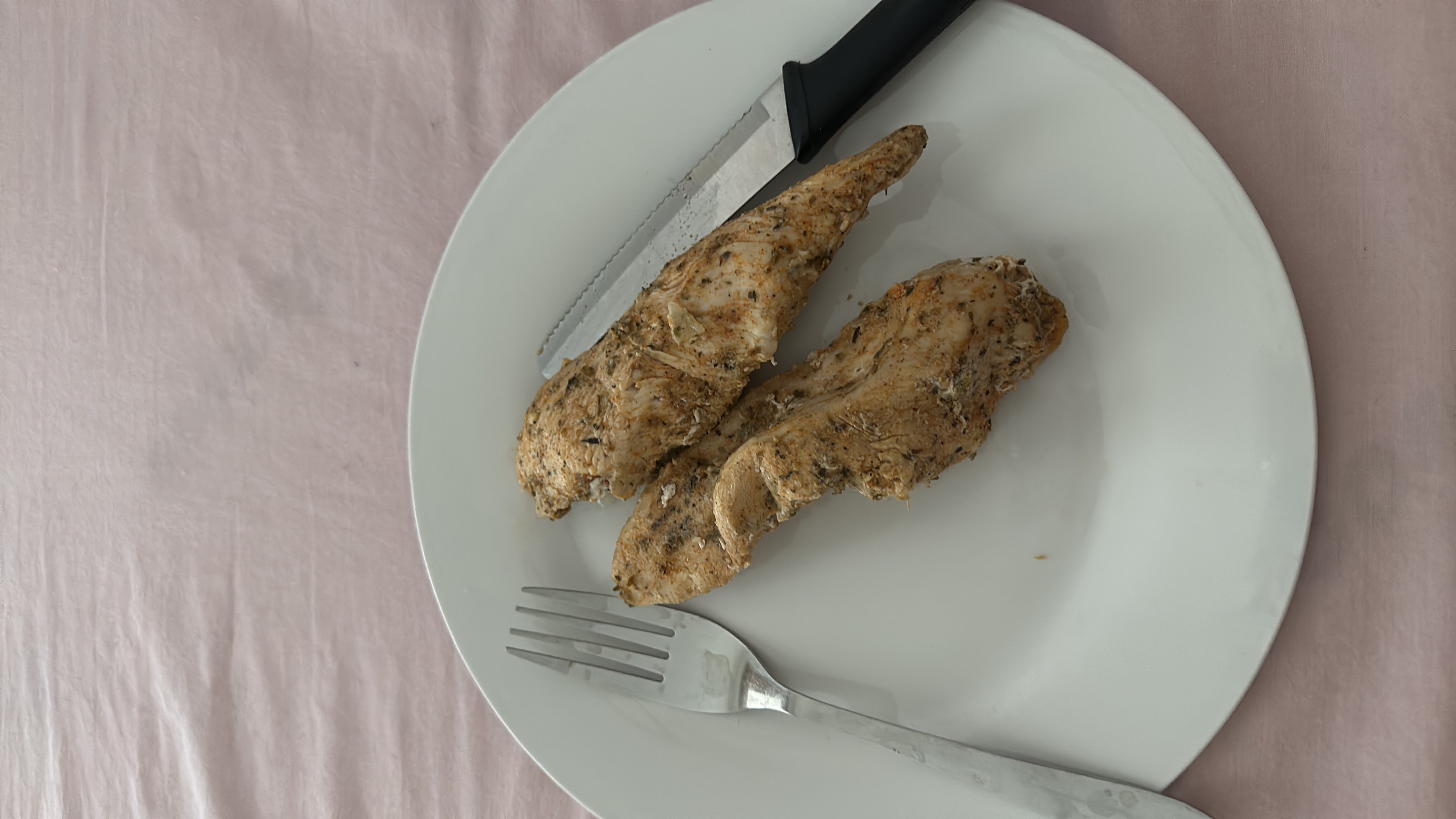 The image shows a plate with two pieces of seasoned and cooked chicken breast, a high-protein and low-carb food.