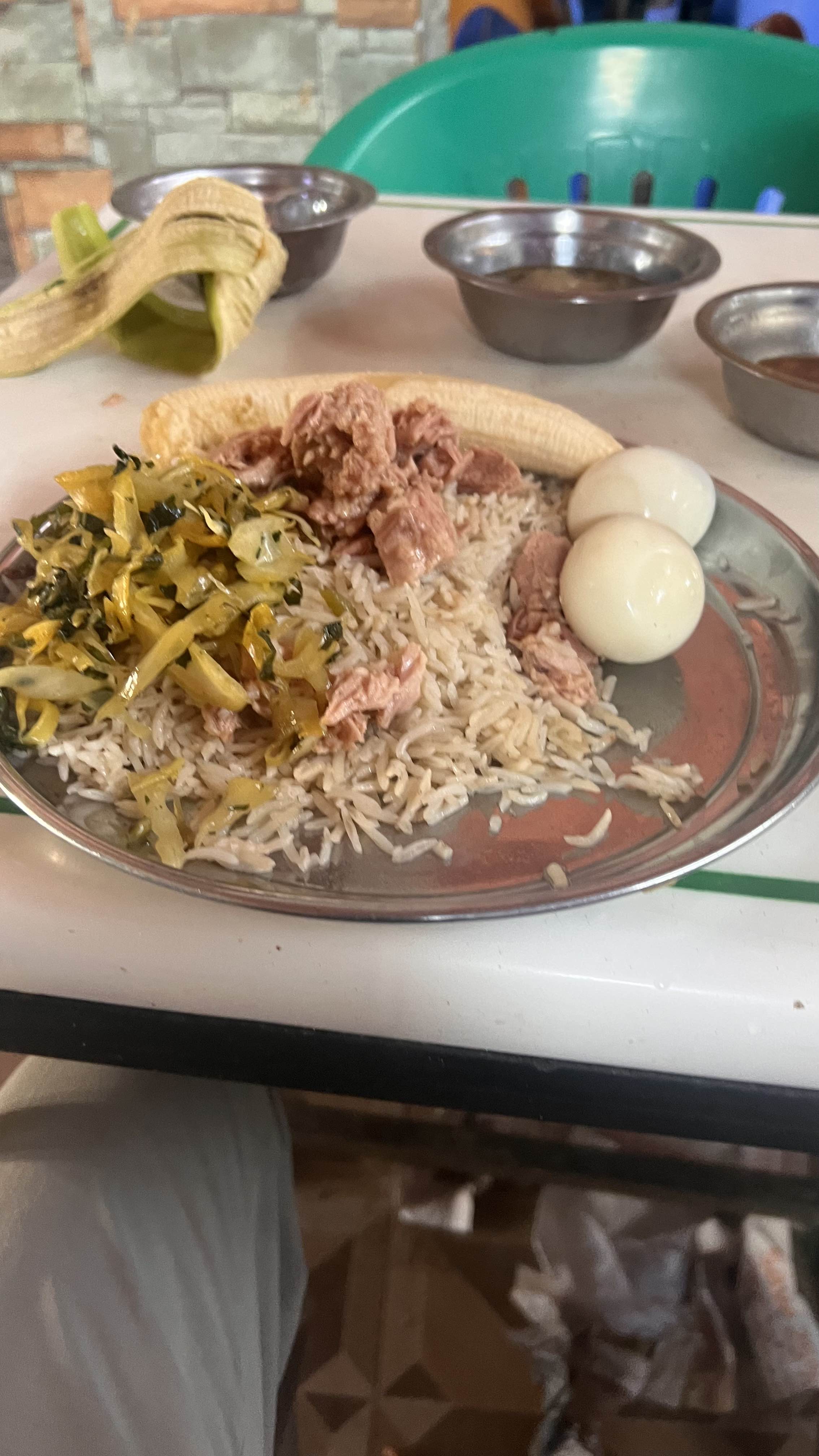 A balanced meal consisting of rice, boiled eggs, cooked greens, cooked meat, and a banana, providing a mix of protein, carbohydrates, and fats.
