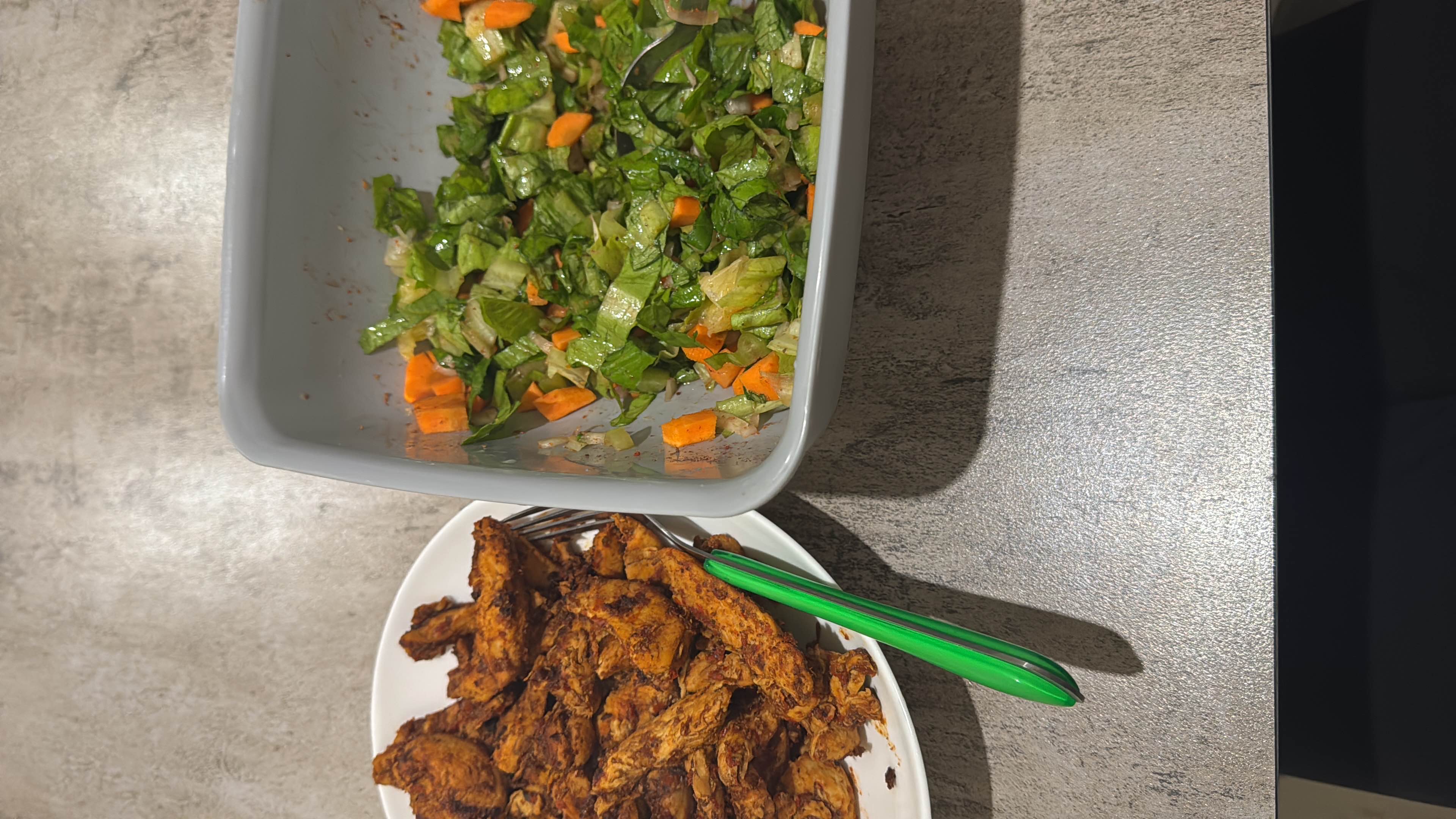 A meal consisting of grilled chicken and a fresh mixed salad with carrots and lettuce, providing a balanced nutritional profile.