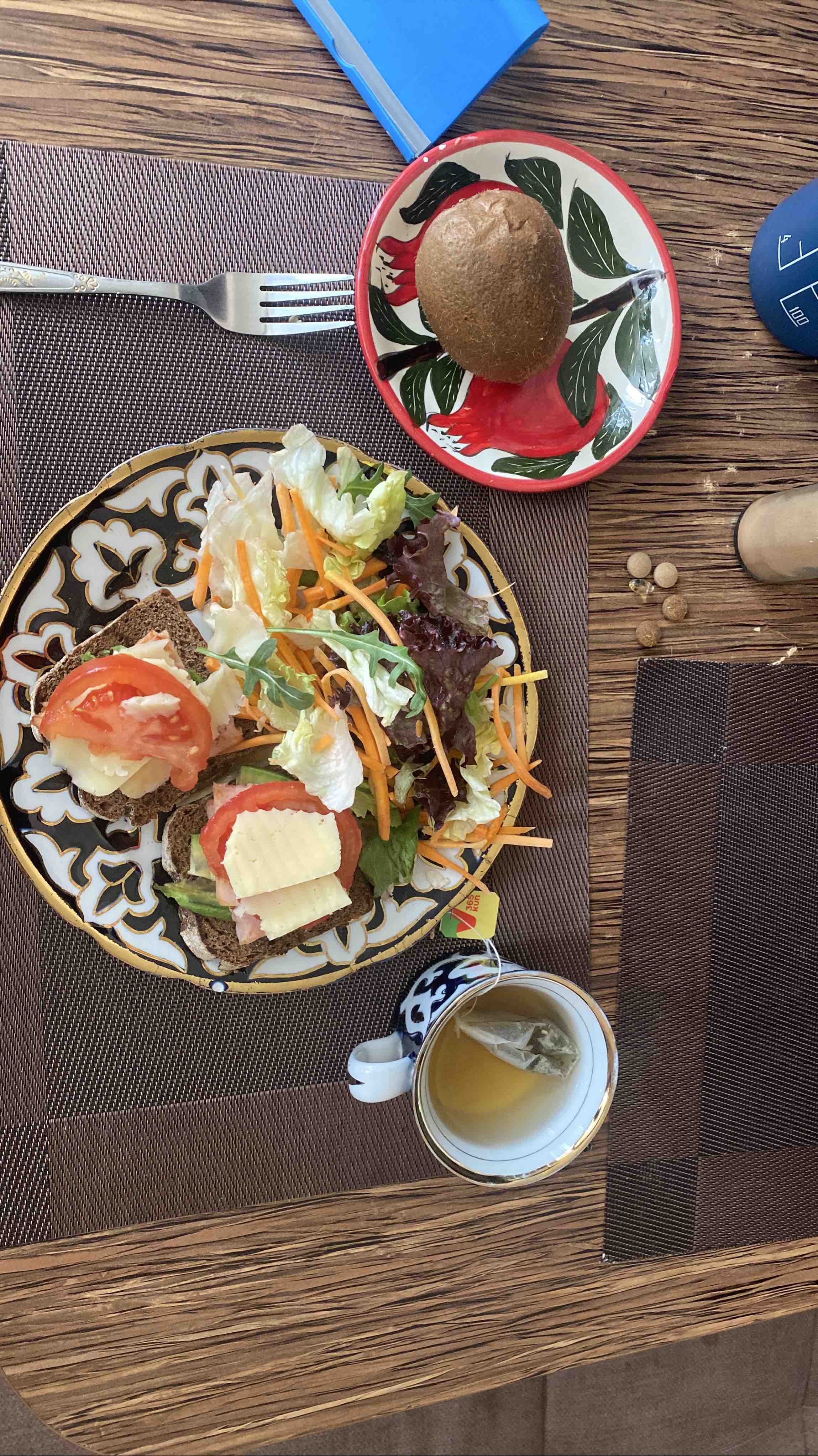 A balanced meal with bread, cheese, turkey ham, avocado, vegetables, kiwi, tea, collagen bar, and low-fat kefir totaling 575 calories.
