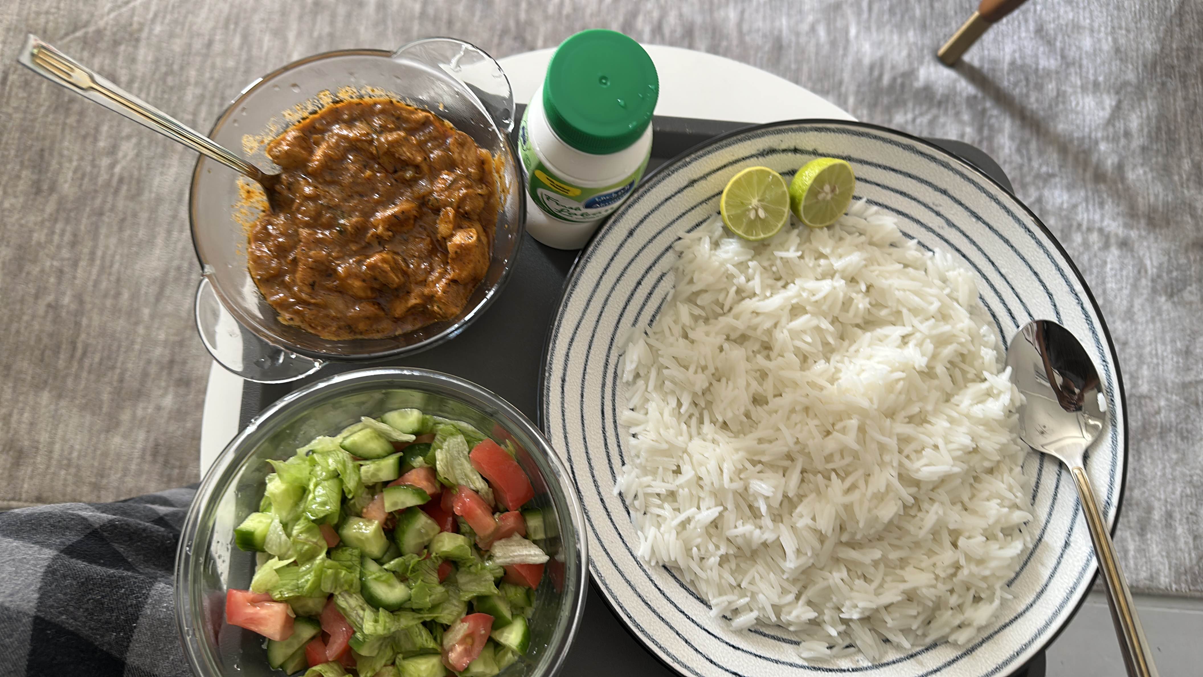 A balanced meal consisting of rice, chicken curry, fresh salad, and a yogurt drink.
