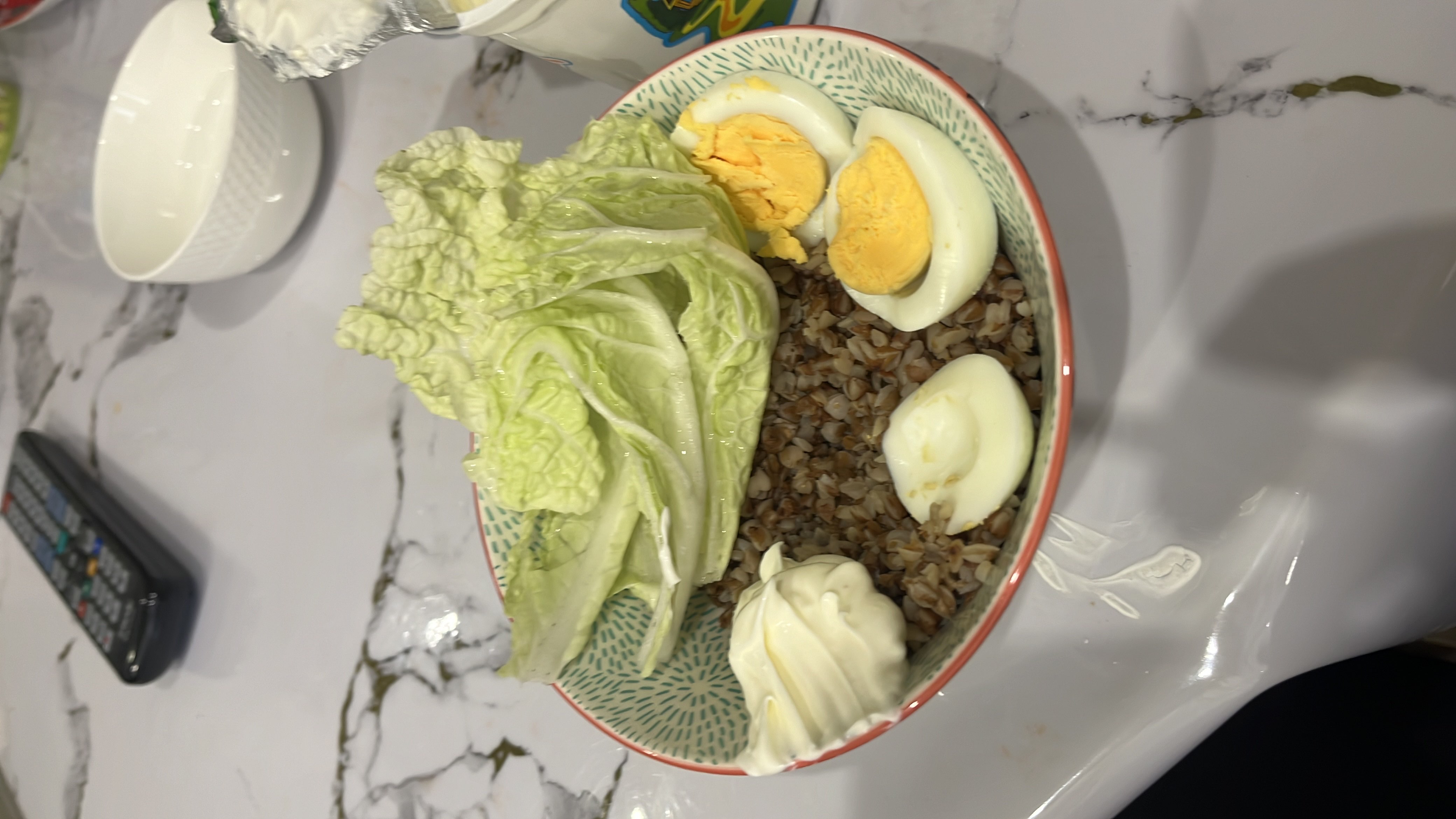 A balanced meal consisting of buckwheat, boiled eggs, lettuce, and sour cream, providing a good mix of protein, carbs, and fats.