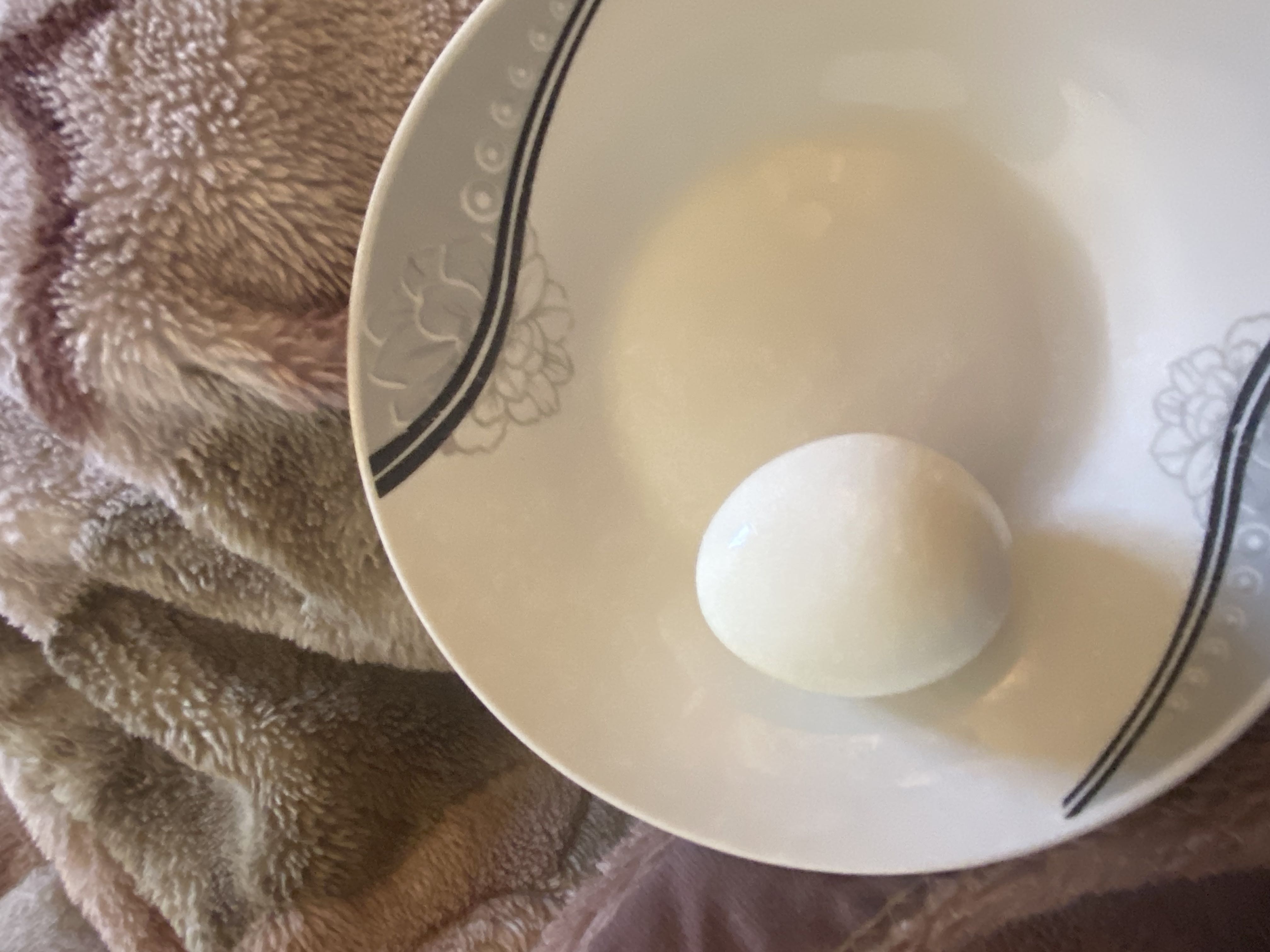The image shows a single boiled egg on a plate, which is a nutritious food item high in protein and healthy fats.