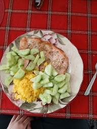 A balanced meal consisting of grilled chicken breast, fresh cucumber slices, and yellow rice.