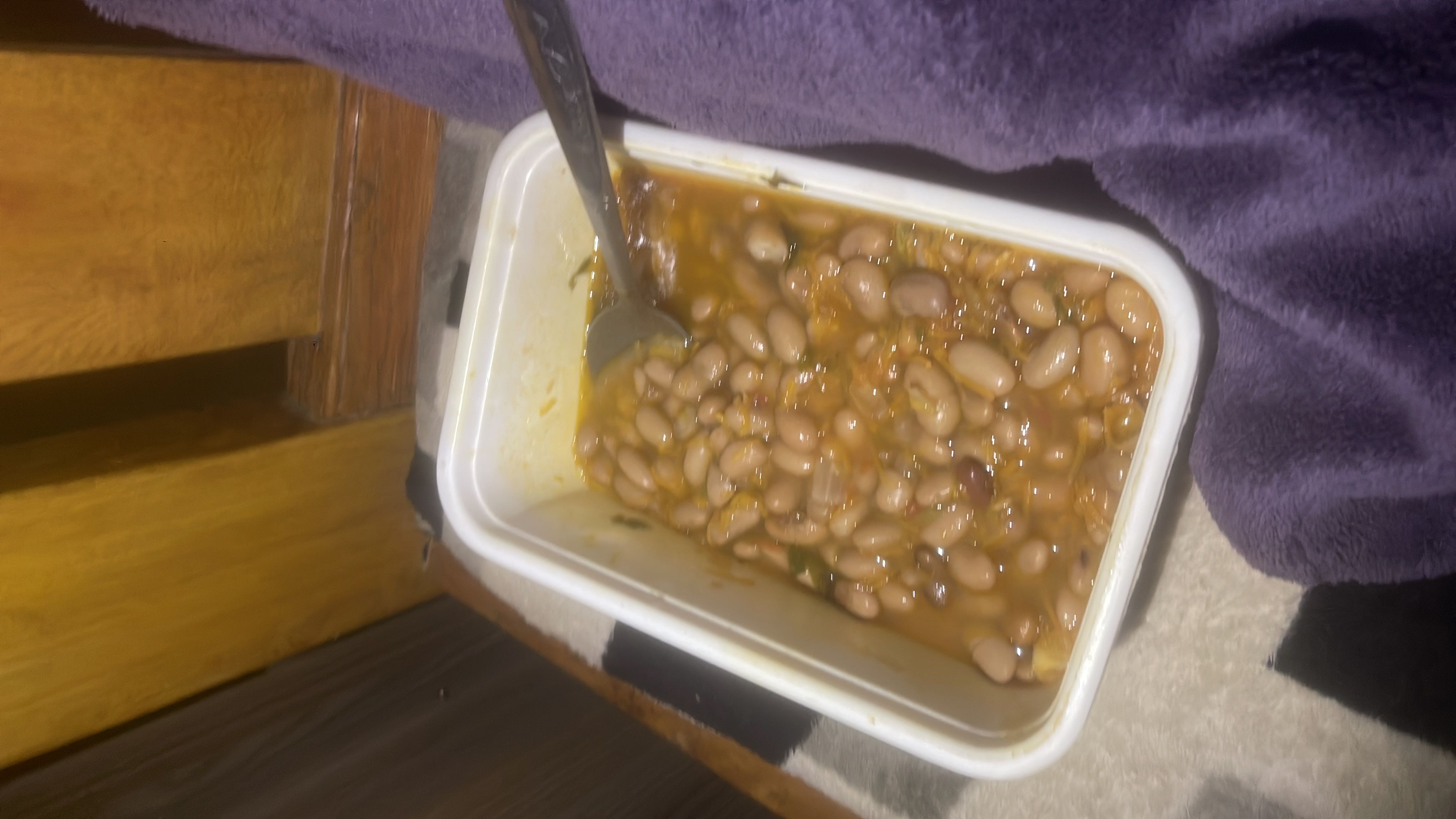 A container of cooked beans in a tomato-based sauce, likely a nutritious and protein-rich dish.