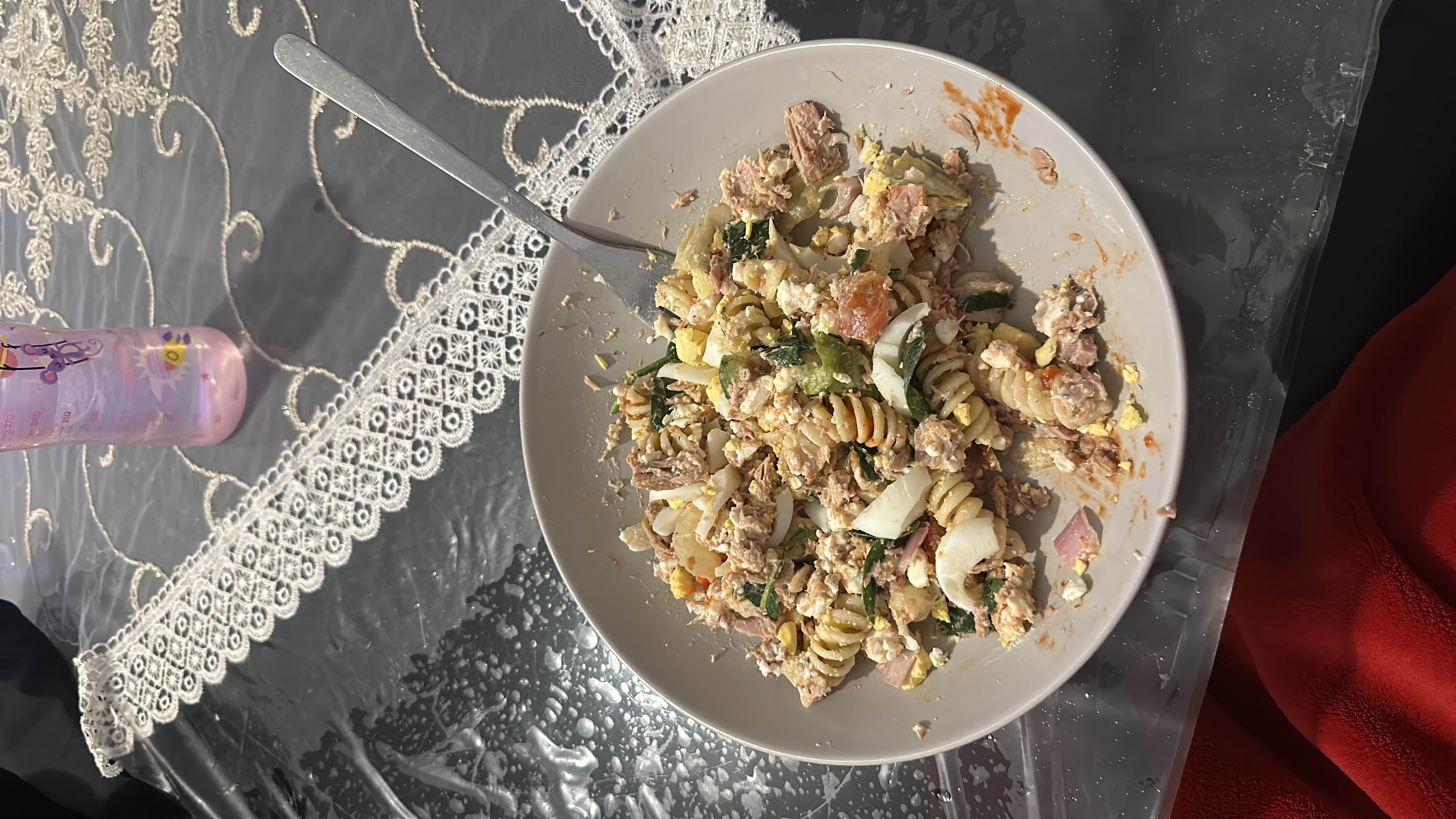 A protein-rich pasta salad with tuna, boiled eggs, spinach, tomatoes, onions, and cheese, providing a balanced mix of macronutrients.