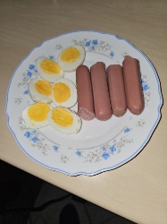The plate contains boiled eggs and sausages, providing a high-protein and high-fat meal with minimal carbohydrates.