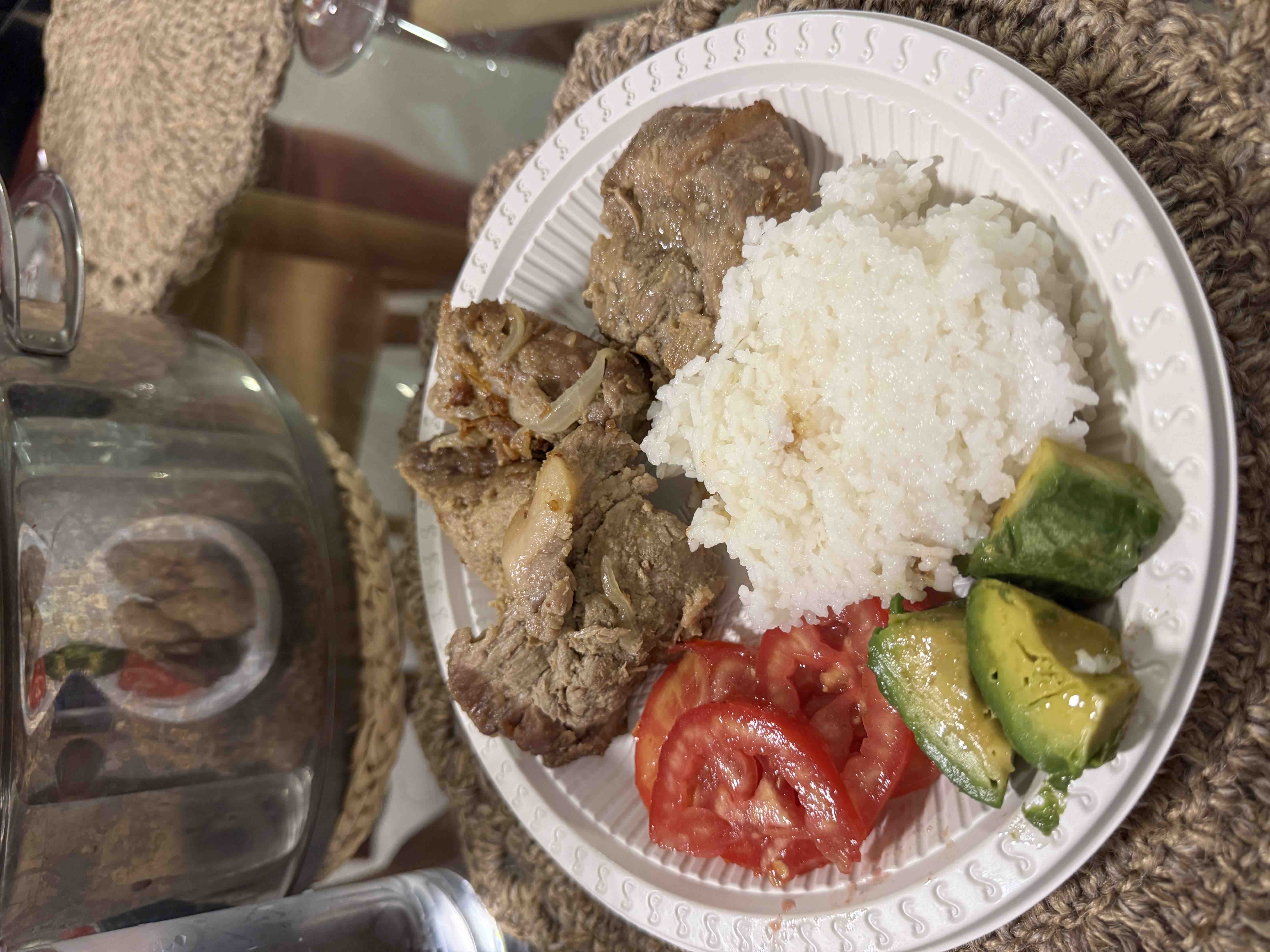 A balanced meal consisting of beef, white rice, fresh tomato slices, and avocado, providing a good mix of protein, carbohydrates, and healthy fats.