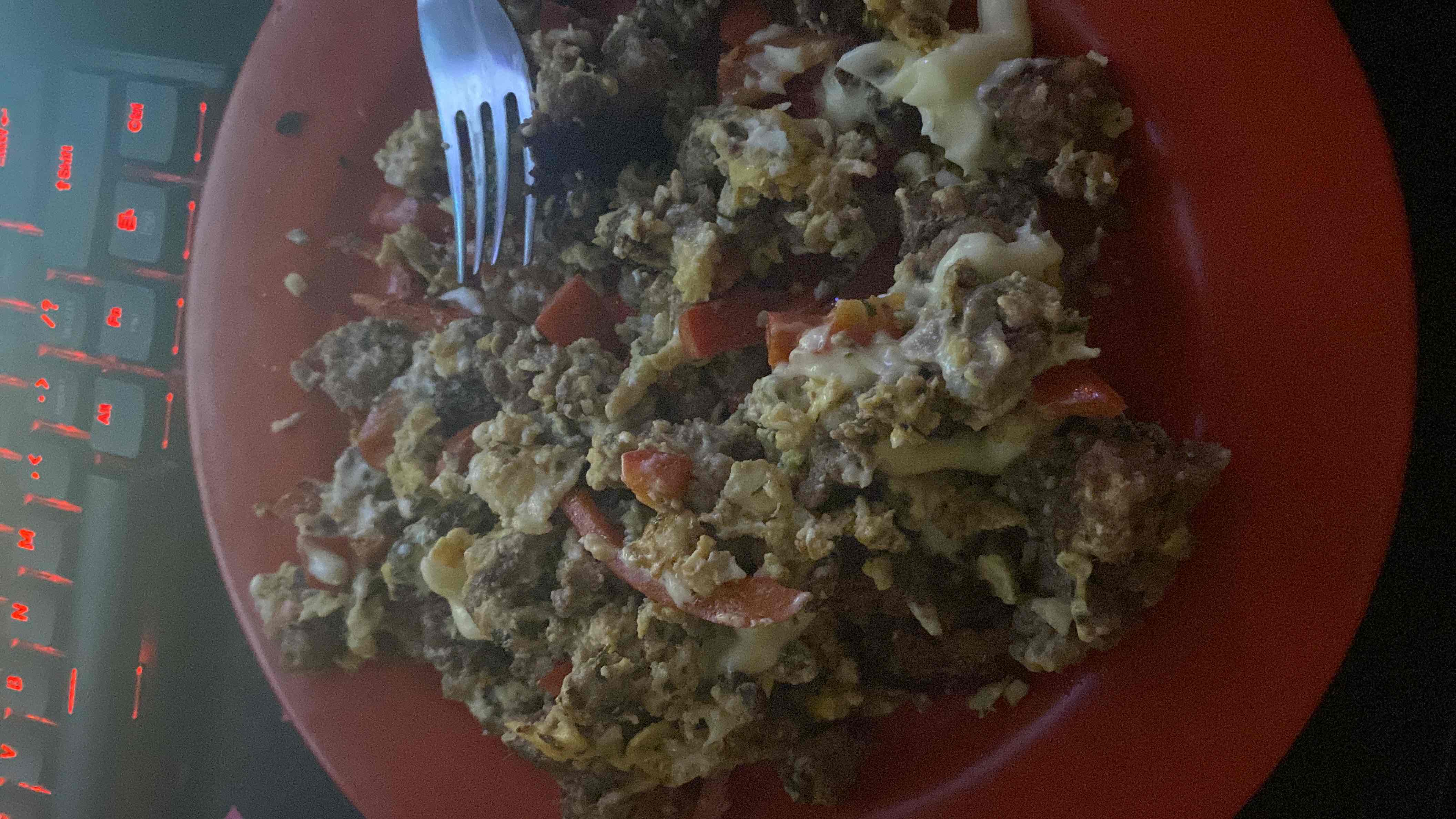 A high-protein meal consisting of scrambled eggs, ground beef, cheese, and vegetables, providing a balanced mix of fats and proteins with moderate carbohydrates.